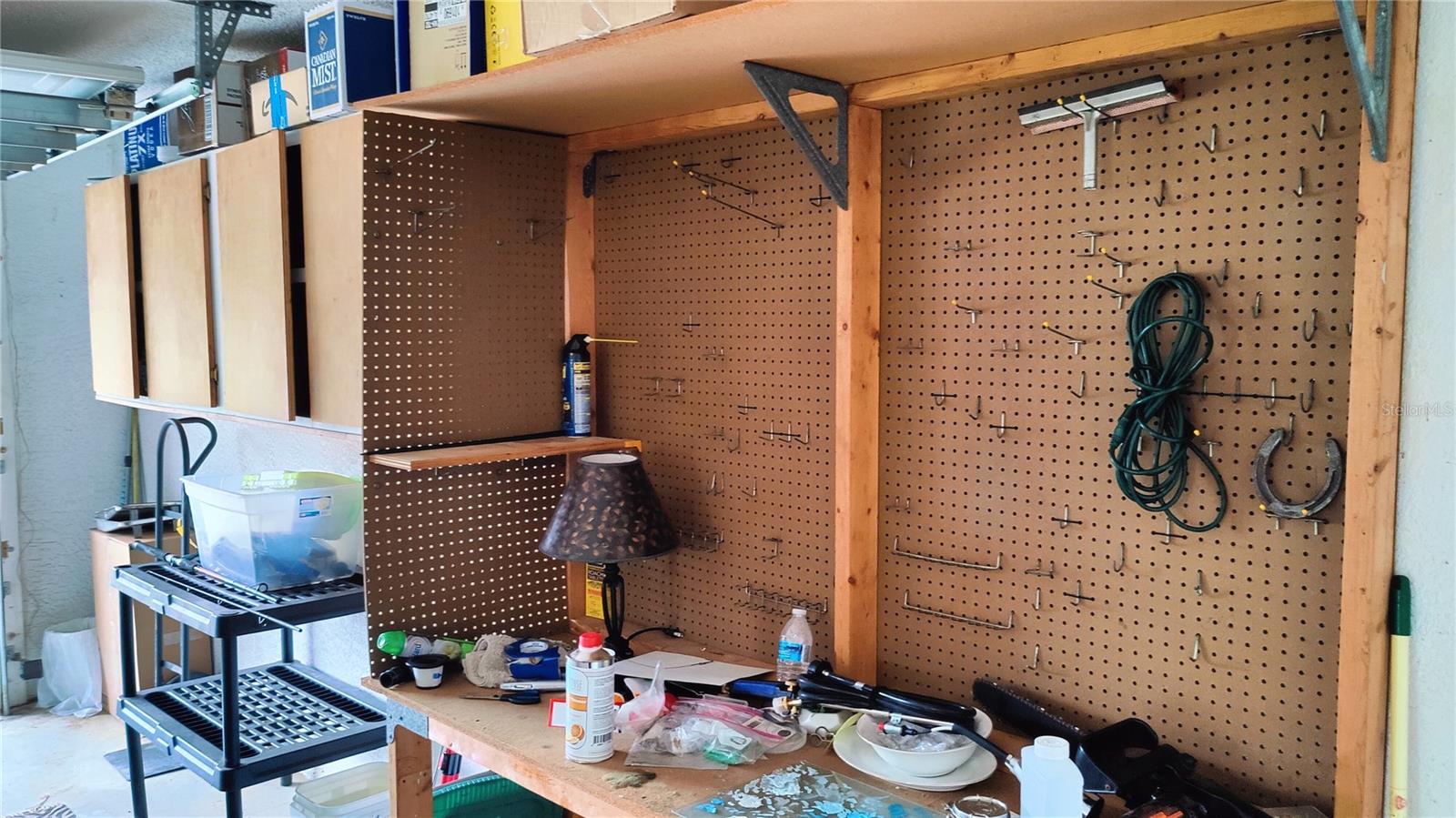 Garage workbench features pegboard for easy tool storage and organization.  Handy storage cabinets on the left