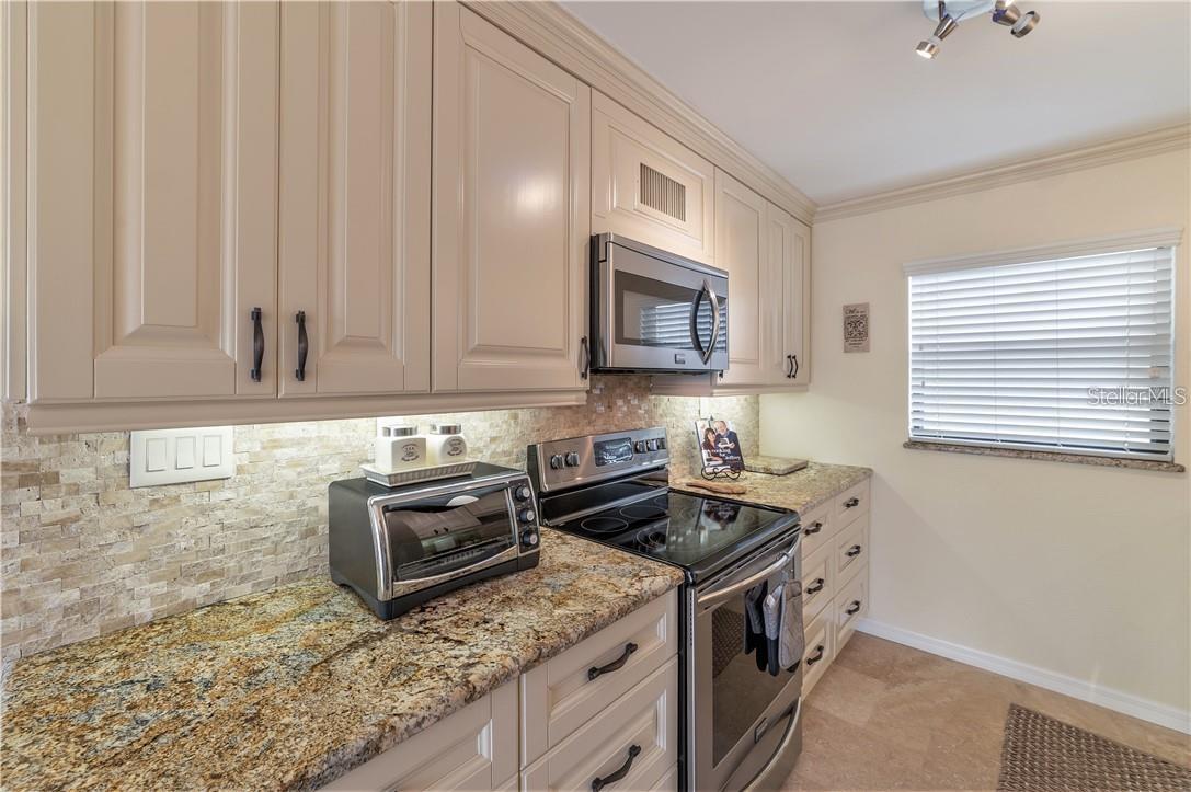 Stainless steel appliances and granite countertops, attention to detail as shown stone tile backsplash, and travertine flooring.