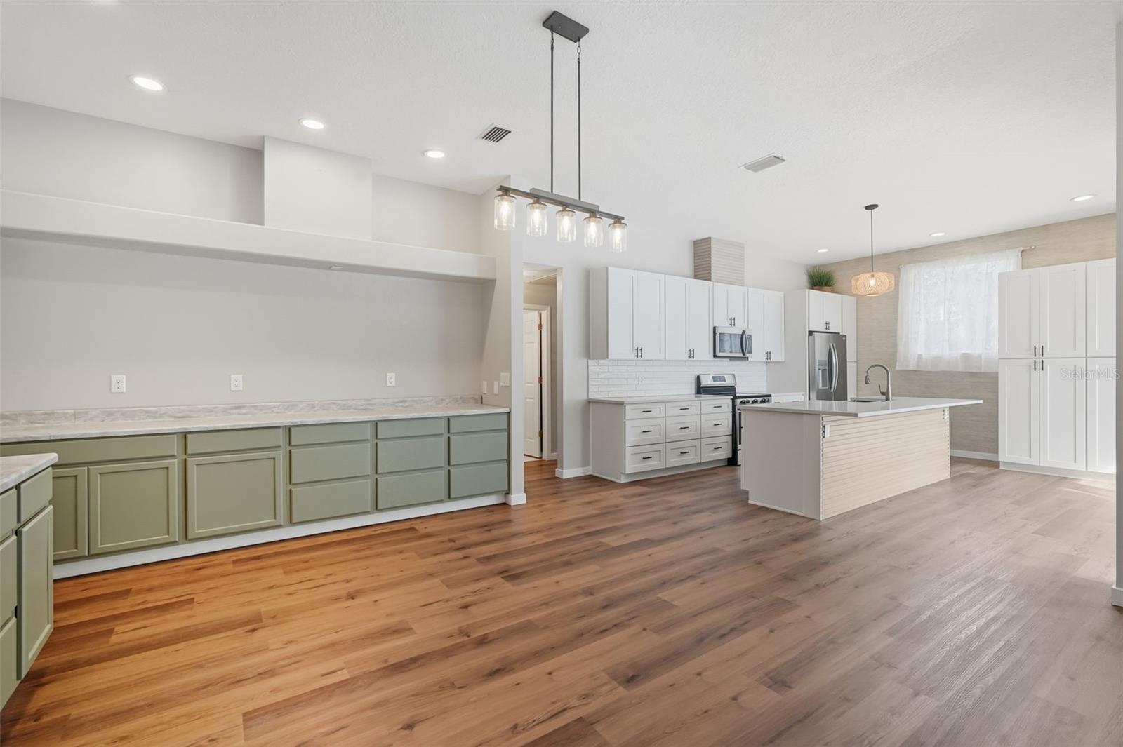 This is the newly renovated kitchen/living area.  This living area could be the living area or dining.  If you have it as living area... a big screen could be on the wall over the green cabinets... family photos on shelves on either side... Small green cabinets to left could be a place for a family computer or bar area.