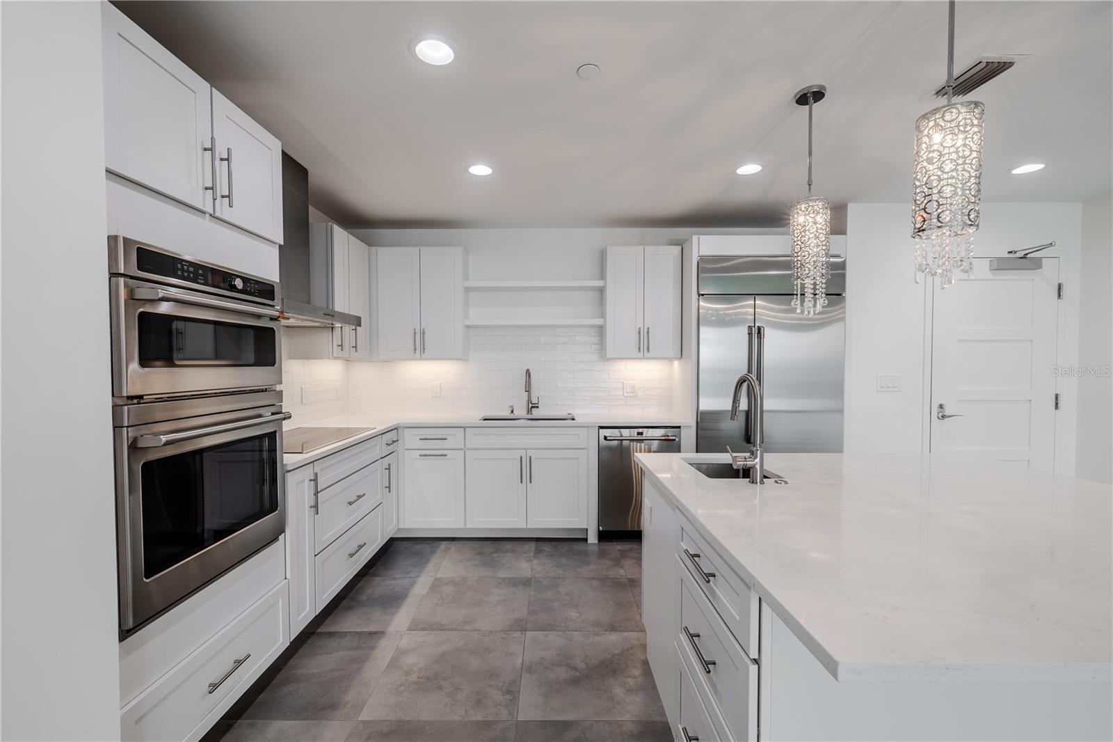 This sophisticated, all-white kitchen exudes modern elegance with its clean lines and luxury finishes.