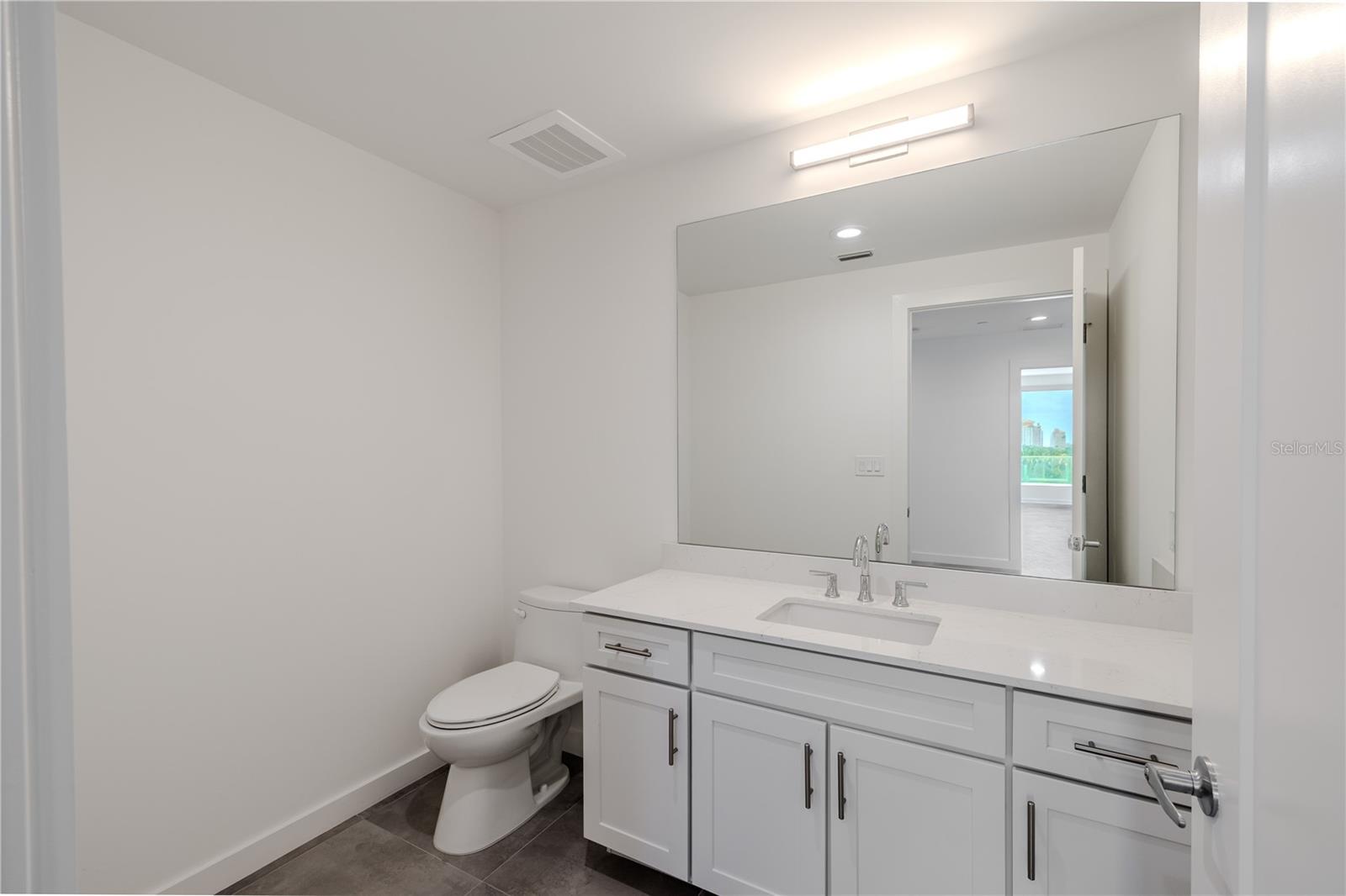 athroom 4 continues the home’s clean, modern aesthetic with a bright, streamlined design. The vanity features shaker-style cabinetry with brushed nickel hardware, a sleek quartz countertop, and an undermount sink complemented by polished chrome fixtures.A large, framed mirror and contemporary lighting create a well-lit, sophisticated atmosphere, while neutral tile flooring adds warmth and durability. Conveniently located near the main living areas and guest quarters, this bathroom offers both function and style — ideal for guests or everyday use.