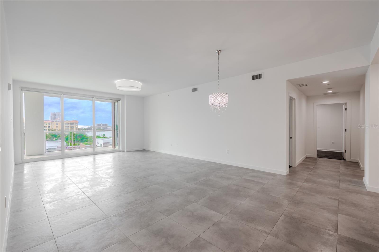 The dining/living room framed by floor to ceiling 'hurricane impact sliders' and a view of the entrance to the primary suite