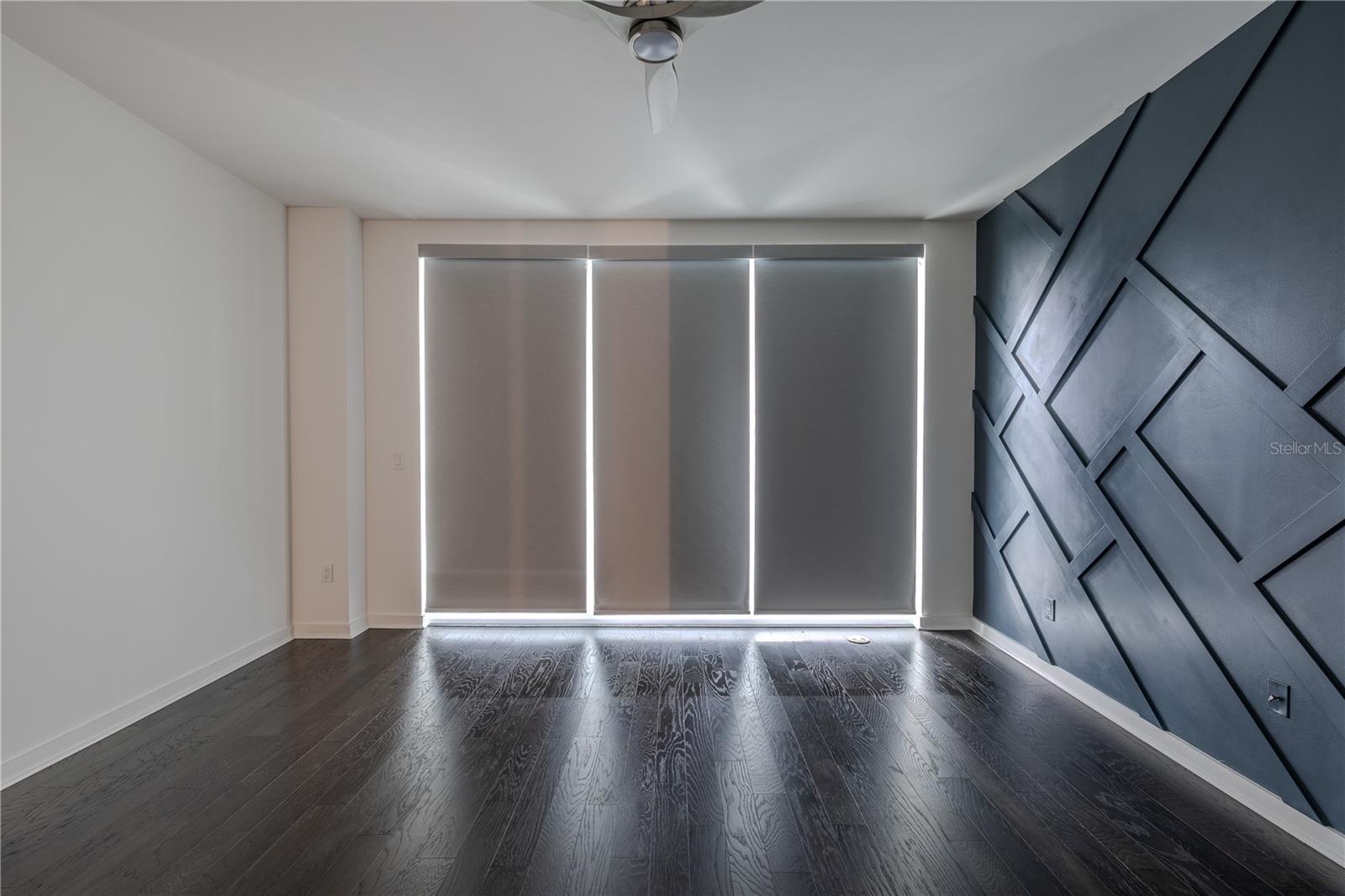 Primary Bedroom: Enjoy the convenience of motorized window shades for effortless privacy and ambiance control. A sleek ceiling fan and clean architectural lines complete this contemporary coastal haven.