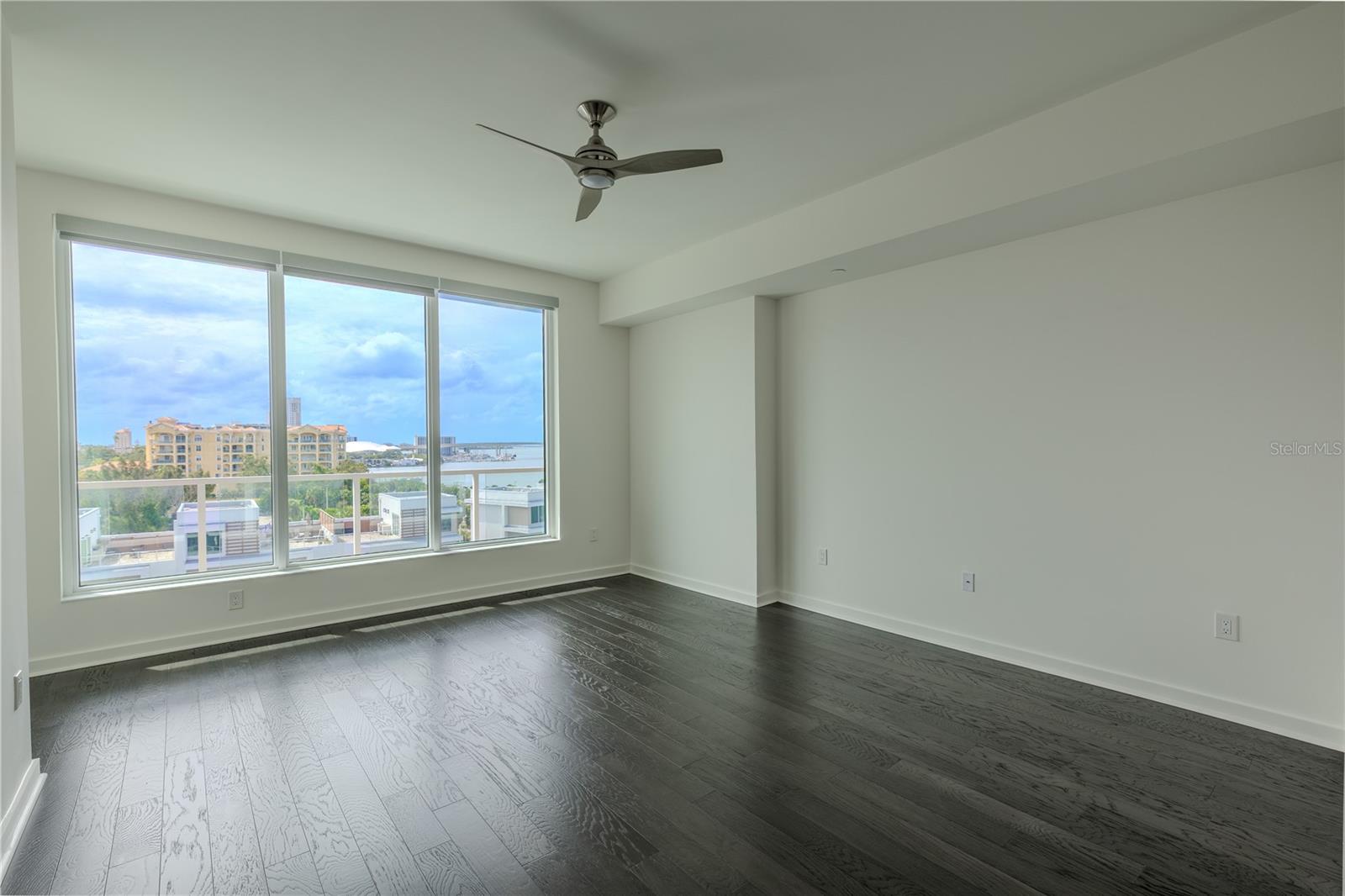 2nd Bedroom: This light-filled bedroom offers sweeping views through a wall of floor-to-ceiling windows that capture both the cityscape and the Intracoastal beyond. Rich hardwood floors and a modern ceiling fan lend a contemporary yet warm feel to the space.
