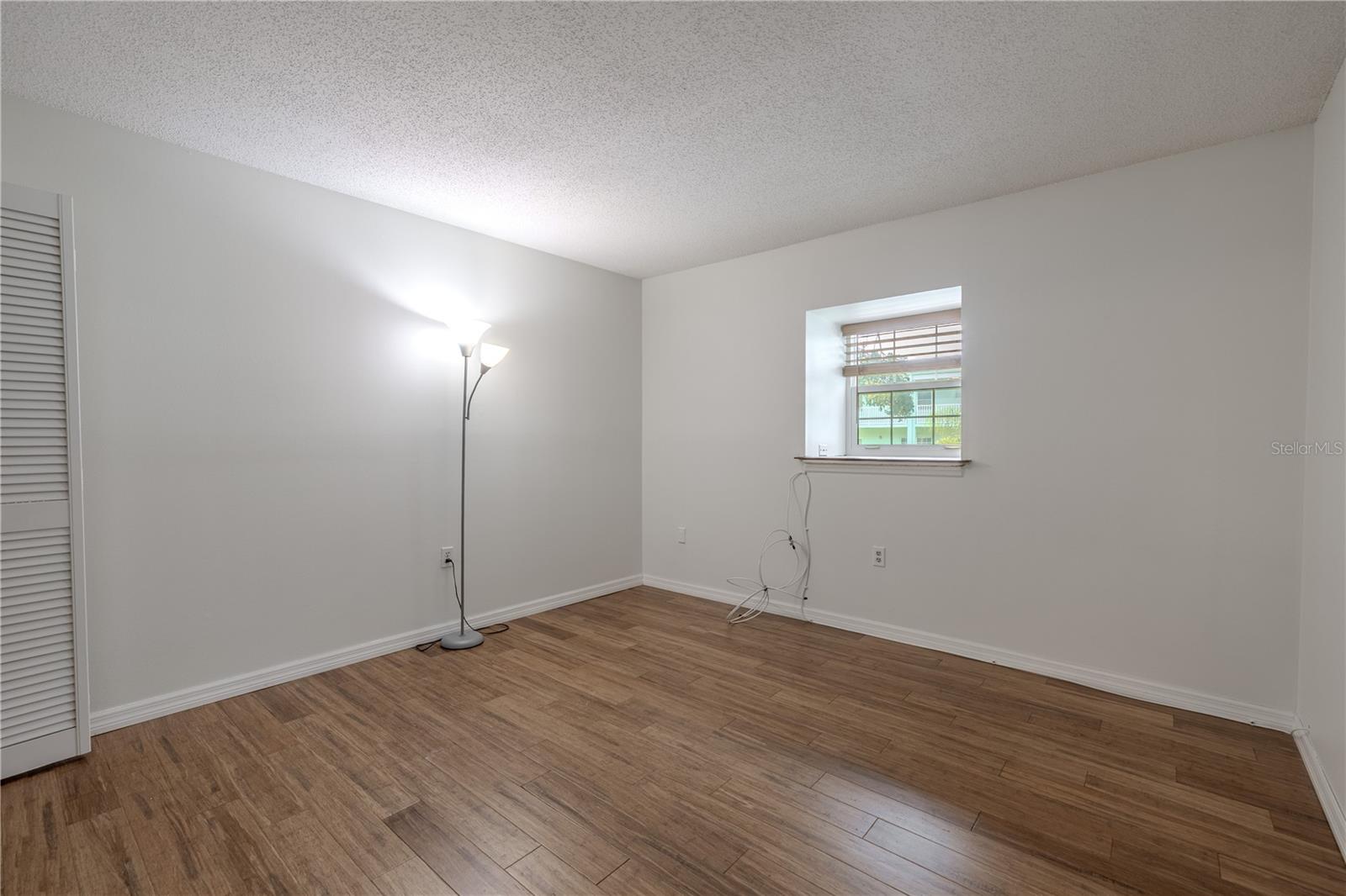 The second bedroom offers a bright and versatile space with warm bamboo flooring and a large double pane window that lets in plenty of natural light. Nuetral walls and clean lines create a crisp, modern feel, while the room’s layout provides flexibility for use as a guest room, home office, or hobby space. A full-size closet adds practical storage