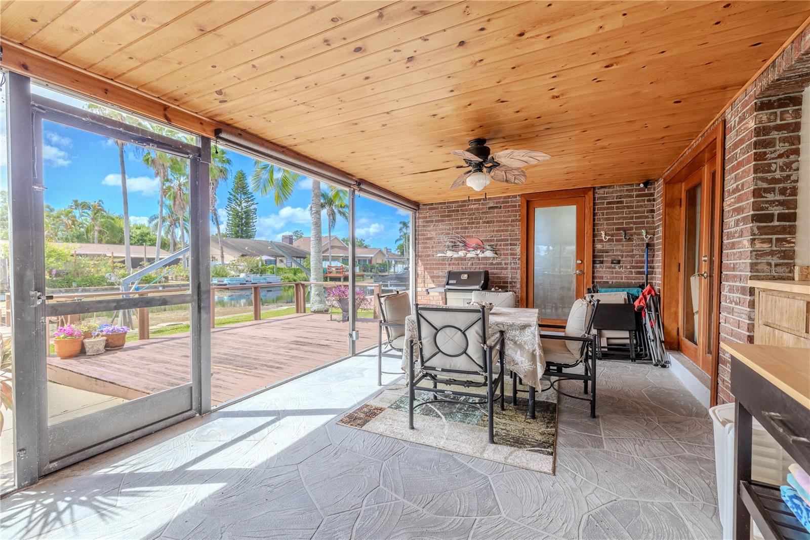 Screened lanai with a wood-paneled ceiling and plenty of space for outdoor dining or lounging.