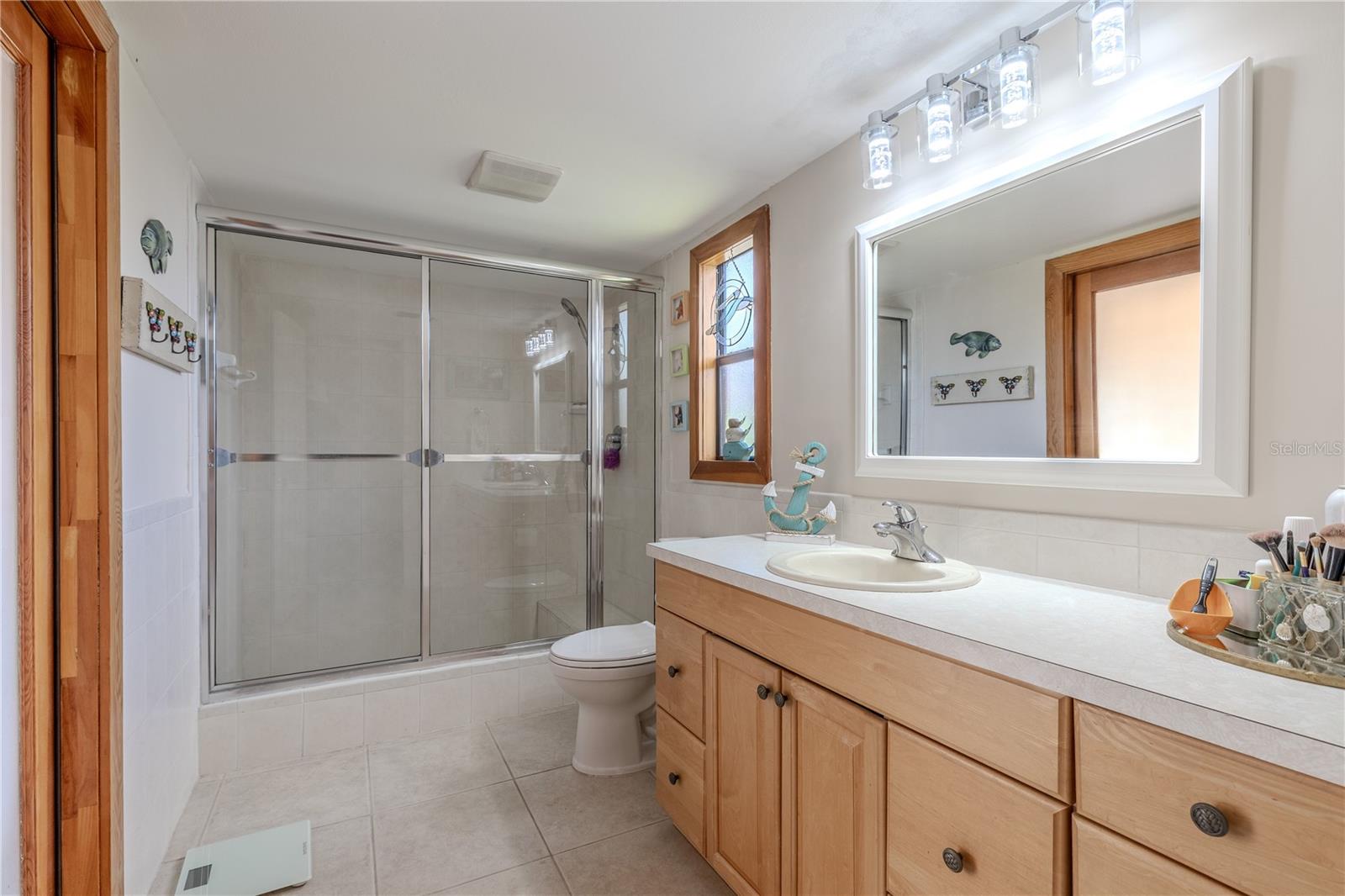 Primary bathroom with extended vanity, glass shower enclosure, and patio access.