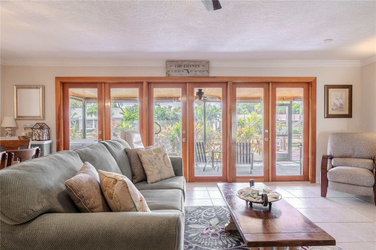 Spacious living room with full tile flooring and a wall of wood-framed doors overlooking the canal.