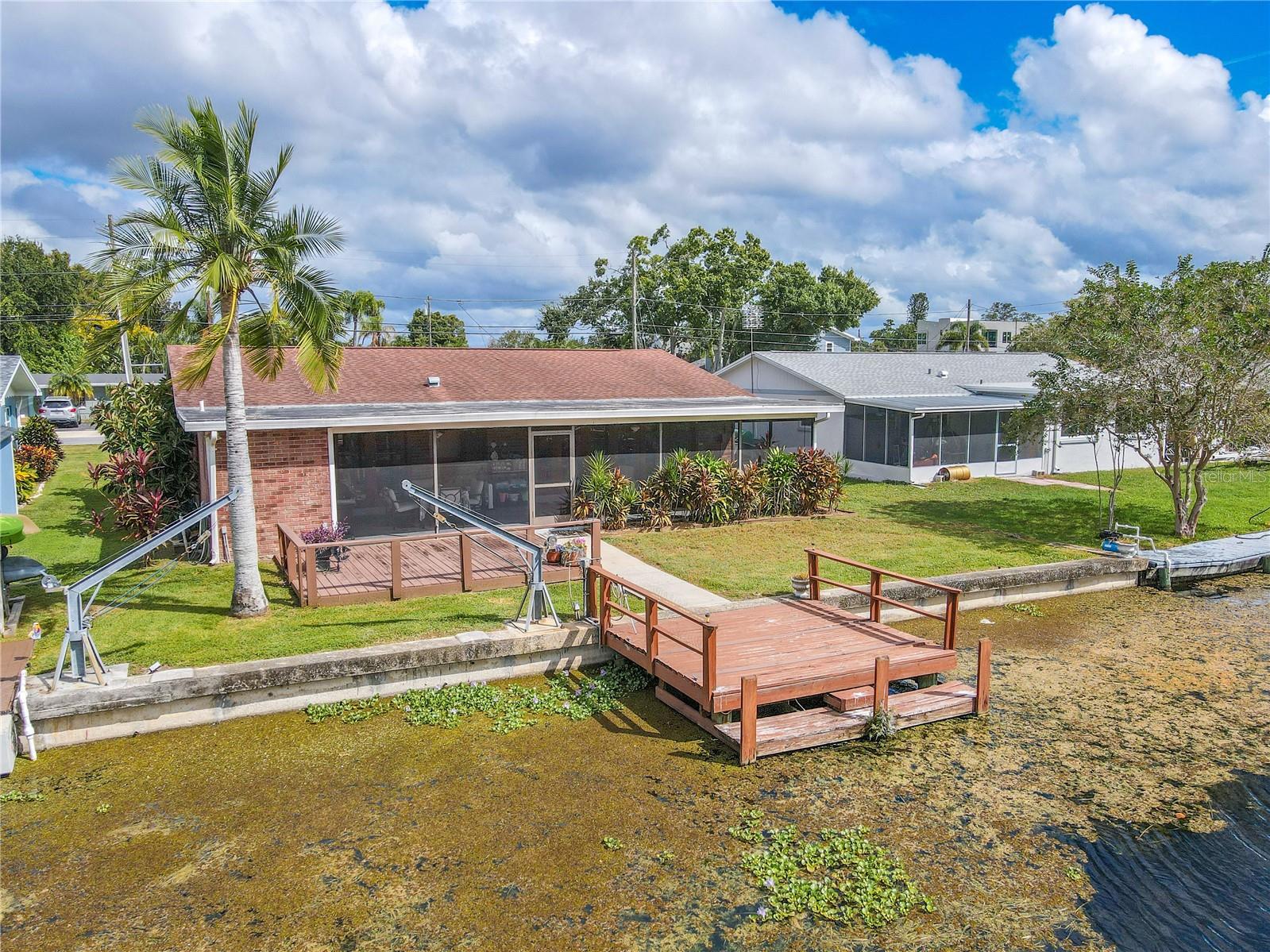 Backyard and dock view showing the home’s brick exterior and connection to the water.