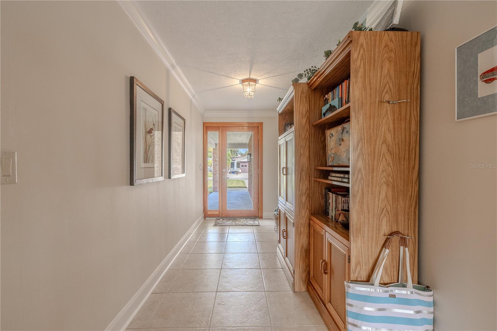 Entry hallway leading into the open living area filled with natural light and tile flooring.