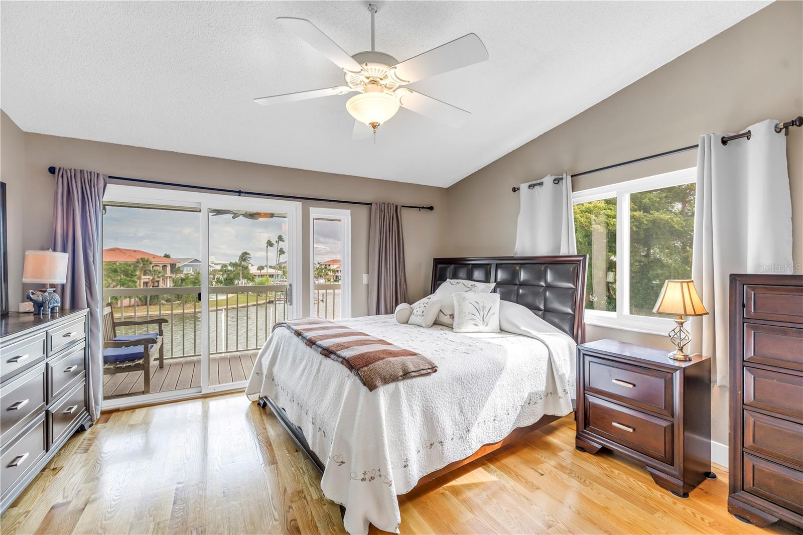 Primary bedroom with wood floors and end unit hurricane impact window and sliding doors