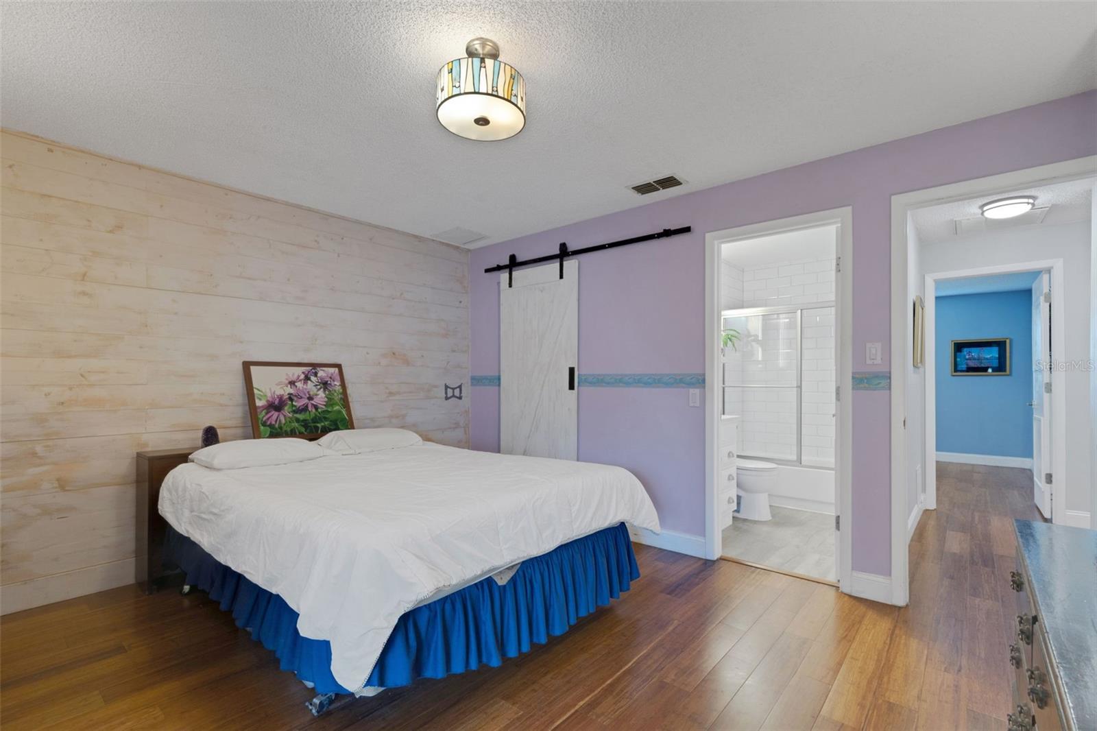Primary Bedroom with en suite, wood plank wall and large walk in closet