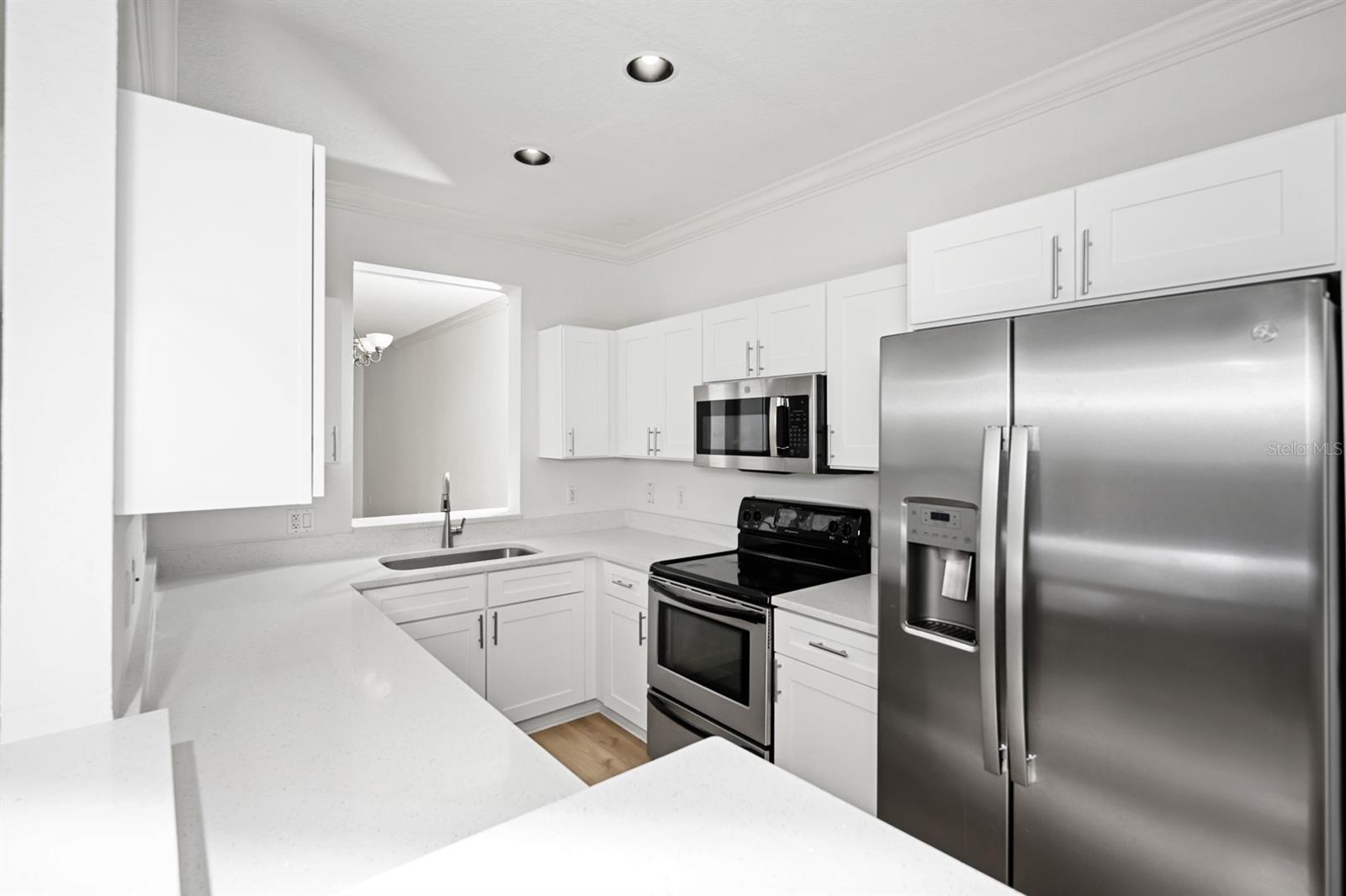 Brand new kitchen with stainless steel fridge, microwave, and range