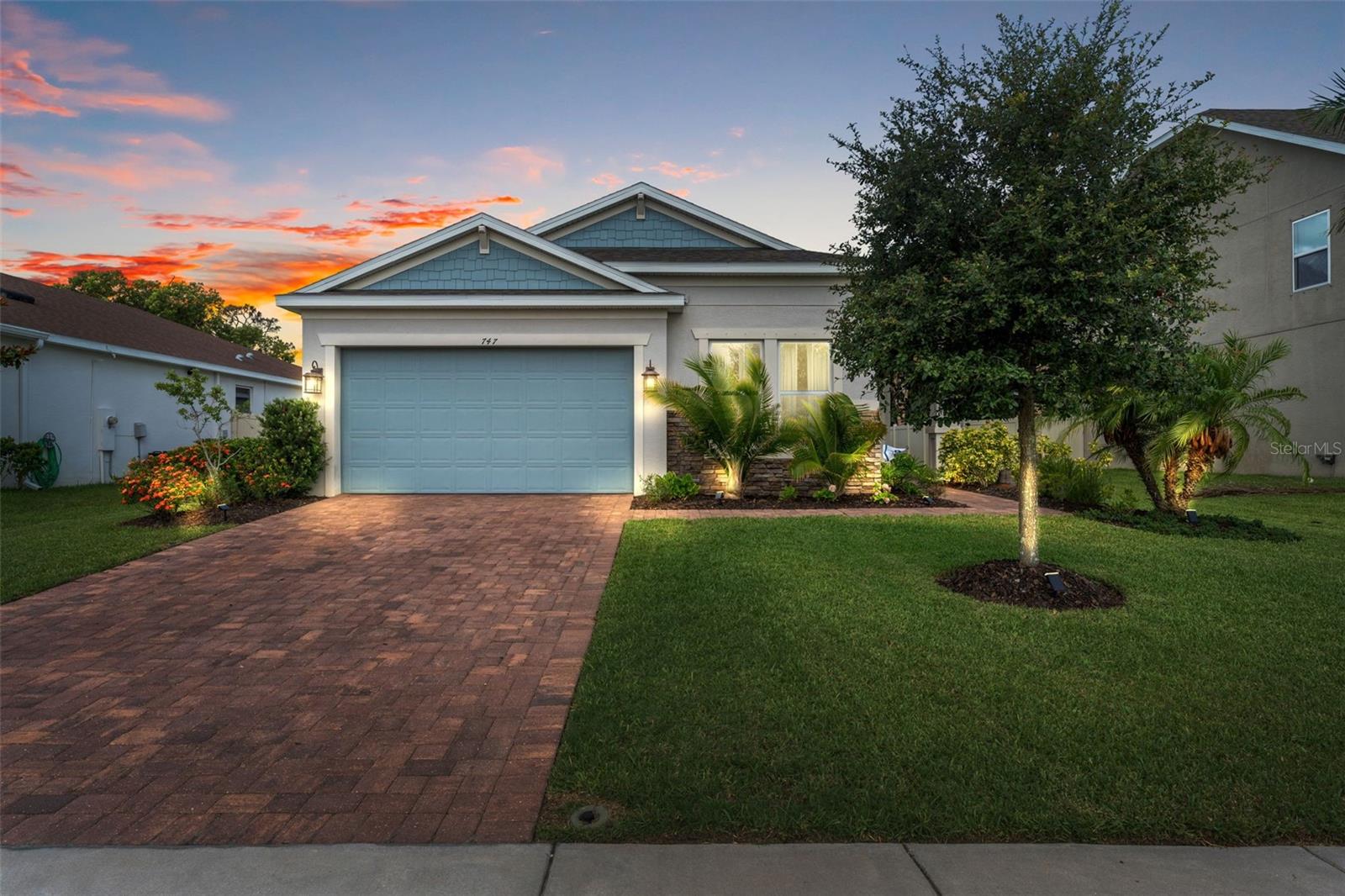 The home’s inviting façade glows at dusk, highlighting elegant exterior lighting and a manicured front yard—showcasing its charm both day and night.