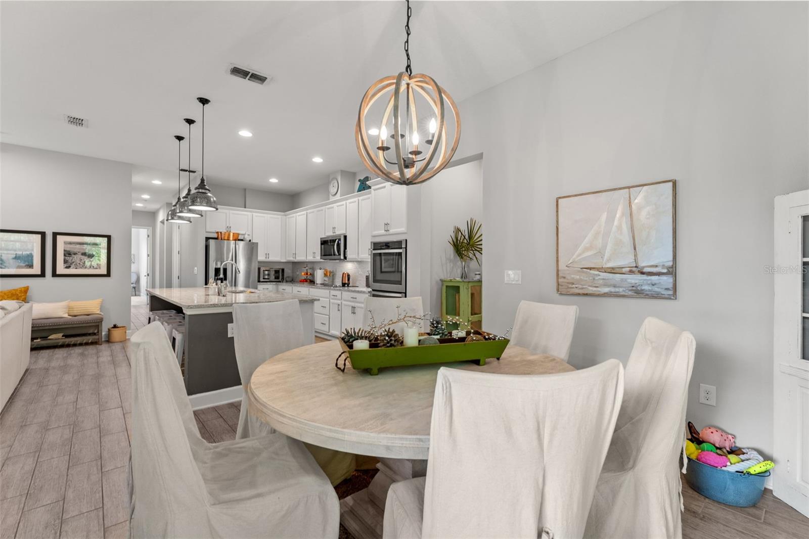 Inviting dining area with warm natural light and a statement chandelier, seamlessly connecting to the kitchen and living room for easy entertaining.