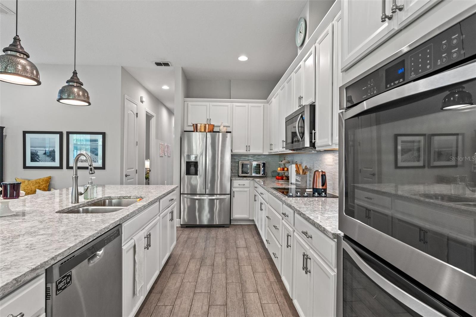 Expansive prep space, double wall ovens, and modern pendant lighting add both function and flair to this gourmet kitchen.