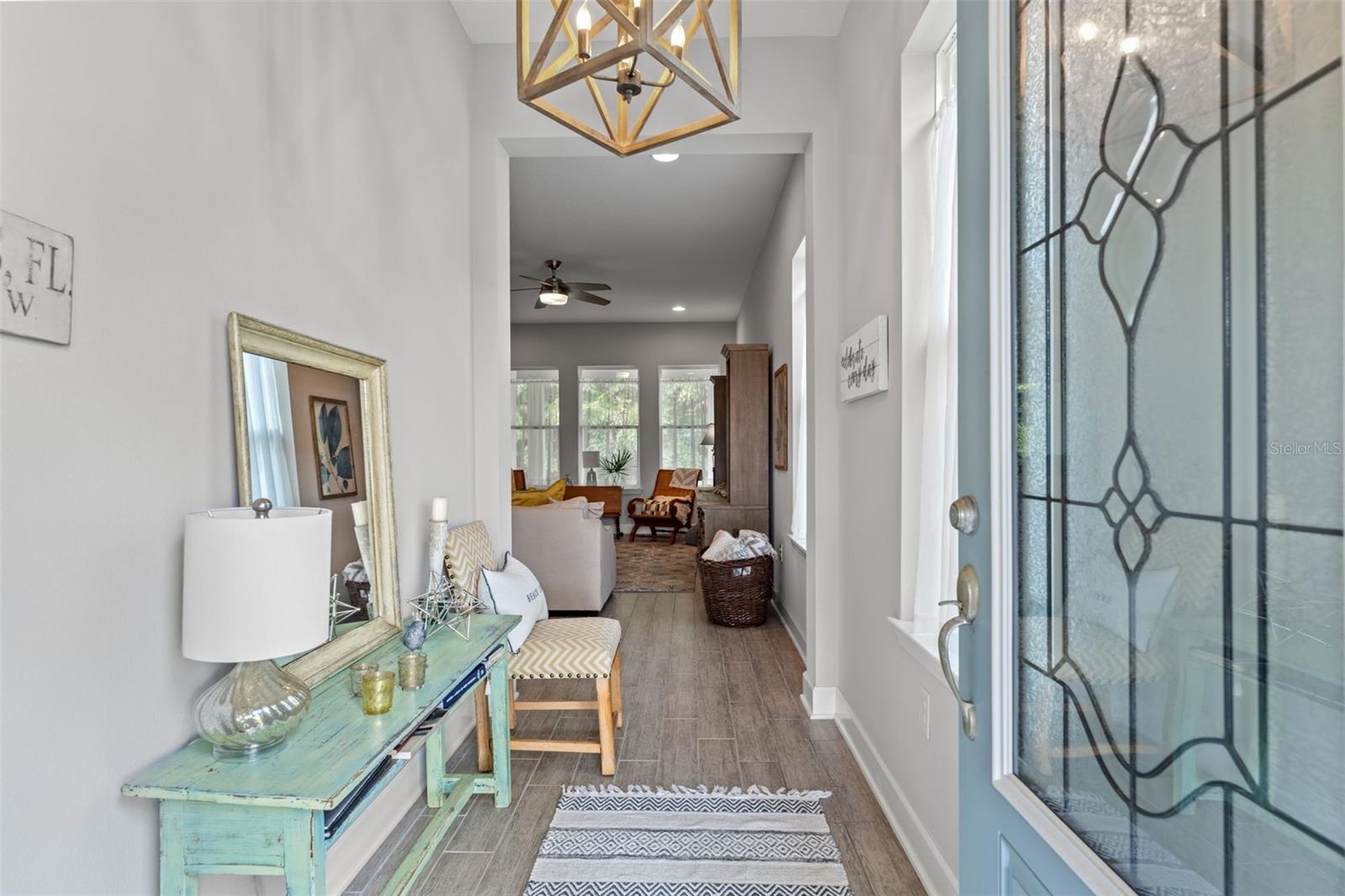 A welcoming entry with decorative glass door, designer light fixture, and wood-look tile flooring that flows seamlessly throughout the main living spaces.