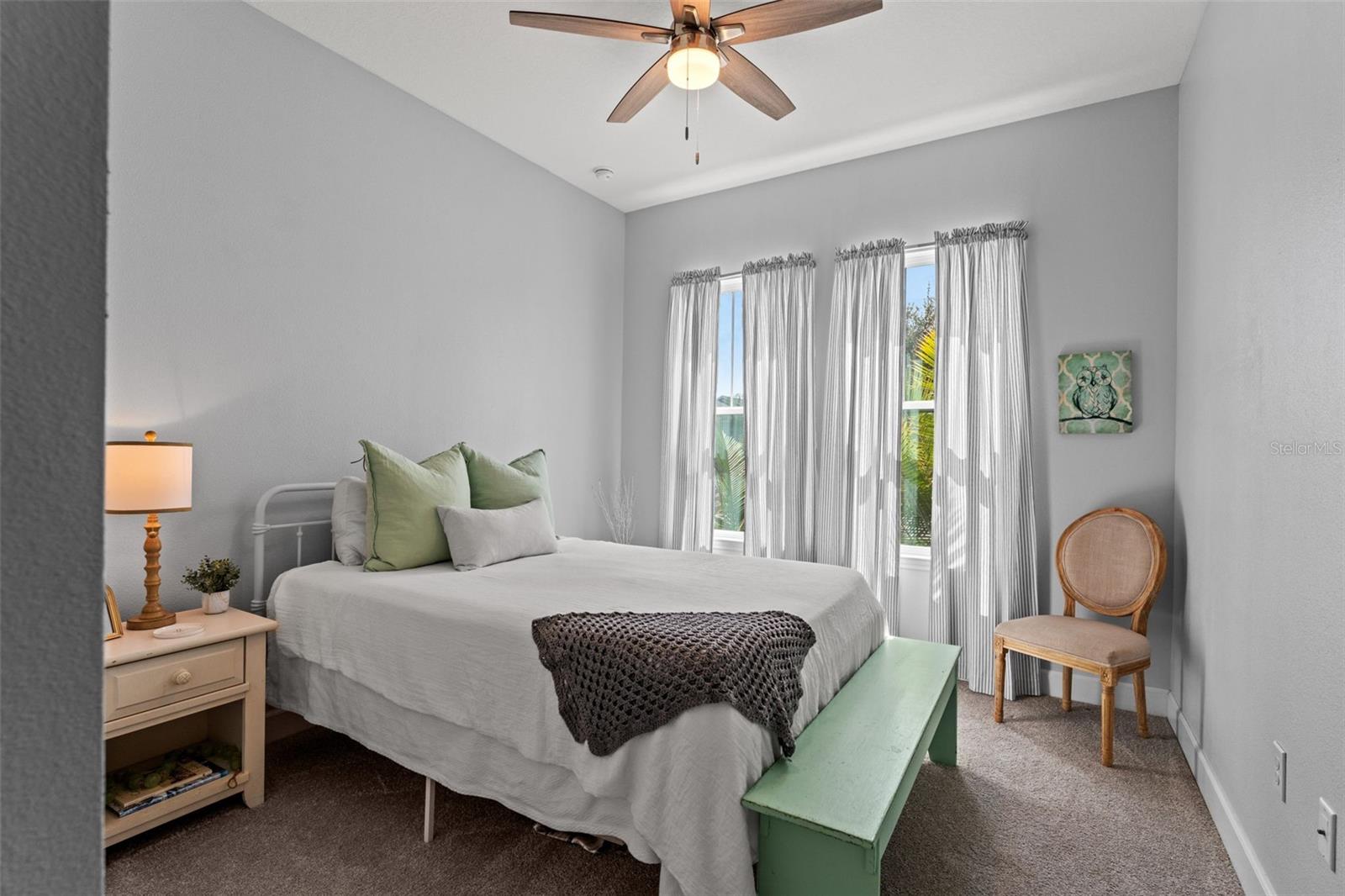 Bright and inviting guest suite with soft neutral tones, large windows, and space for a full or queen bed—ideal for family or overnight guests.