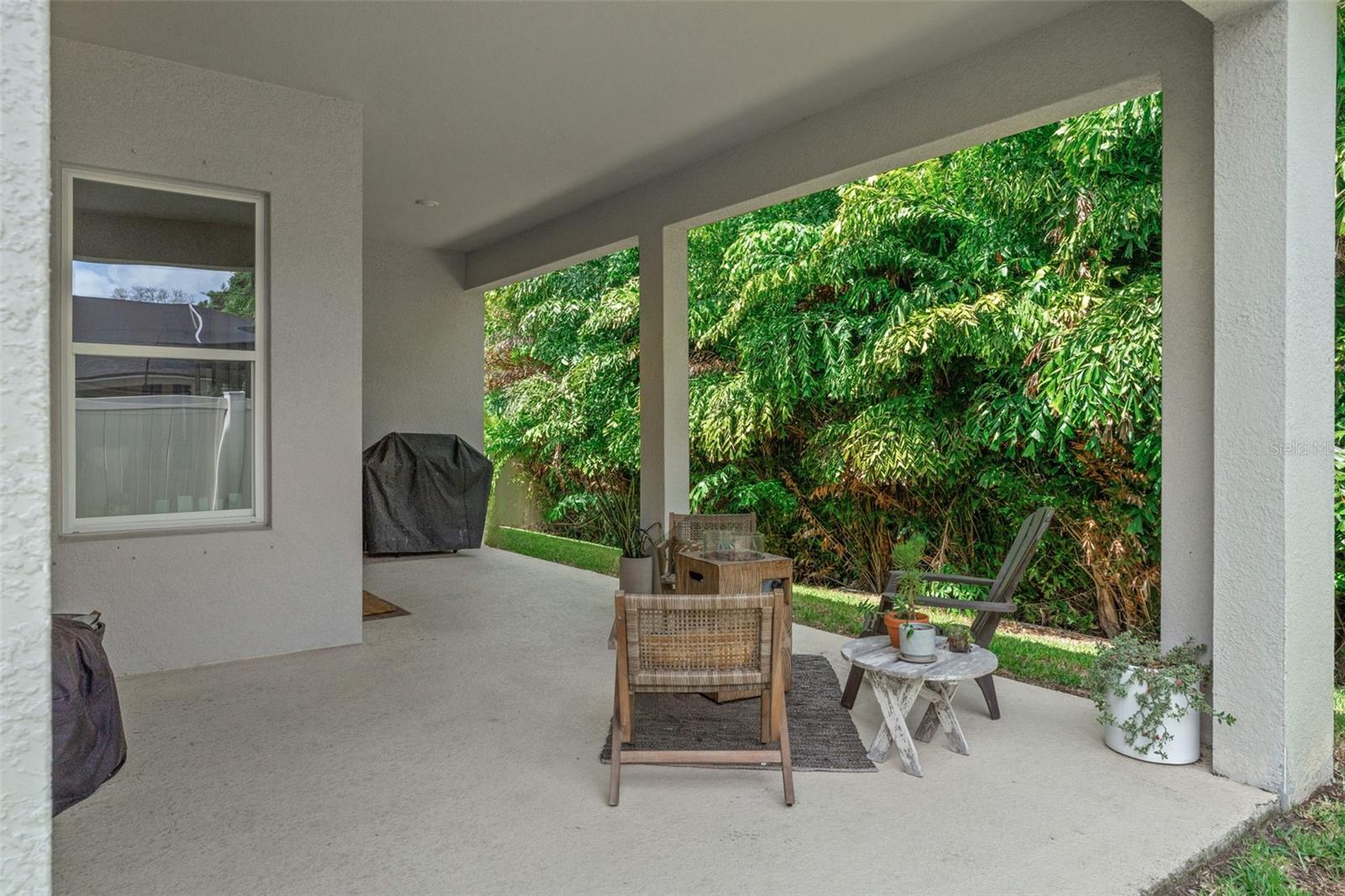 Spacious covered patio overlooking lush greenery, ideal for outdoor dining, grilling, or simply relaxing in the shade.