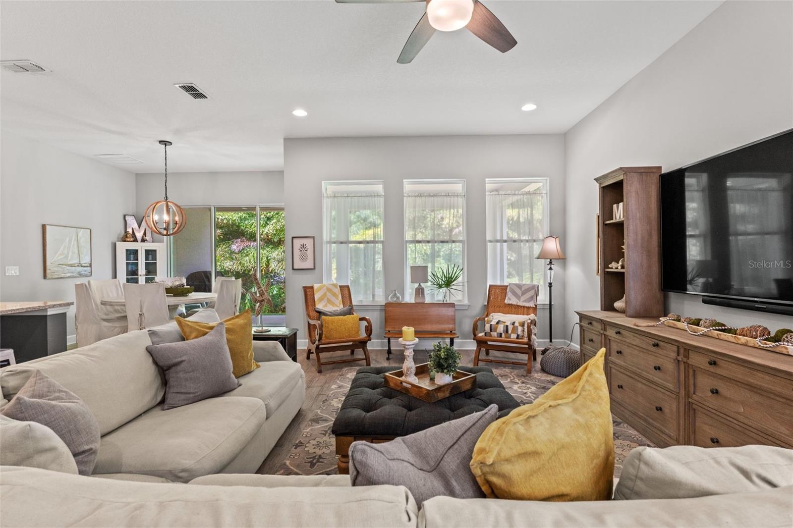 pacious open-concept living area featuring tall ceilings, recessed lighting, and multiple windows that fill the room with natural light. Perfect for relaxing or entertaining.