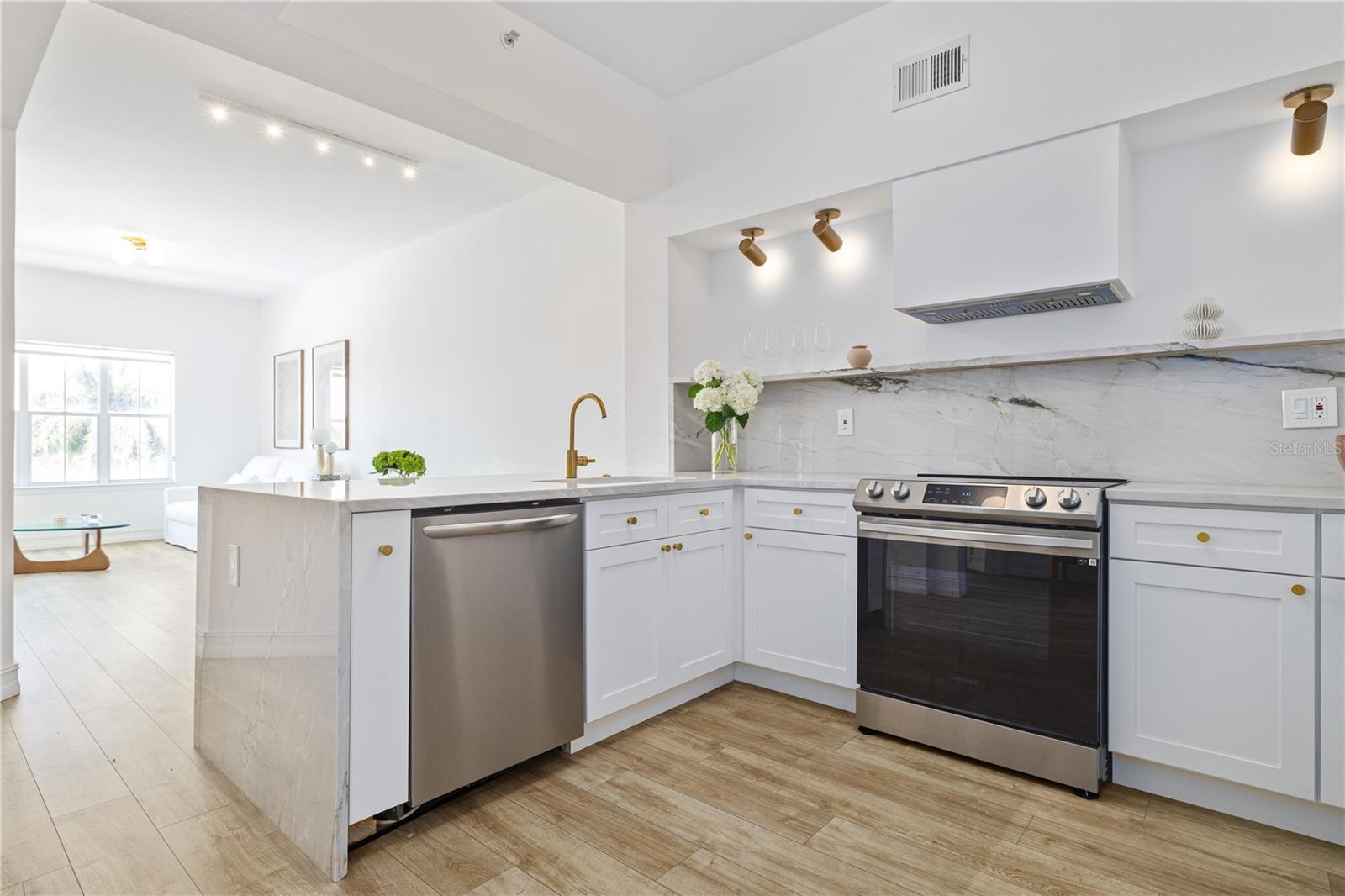 Beautifully renovated kitchen features a breakfast bar with dishwasher, and waterfall edge marble countertops