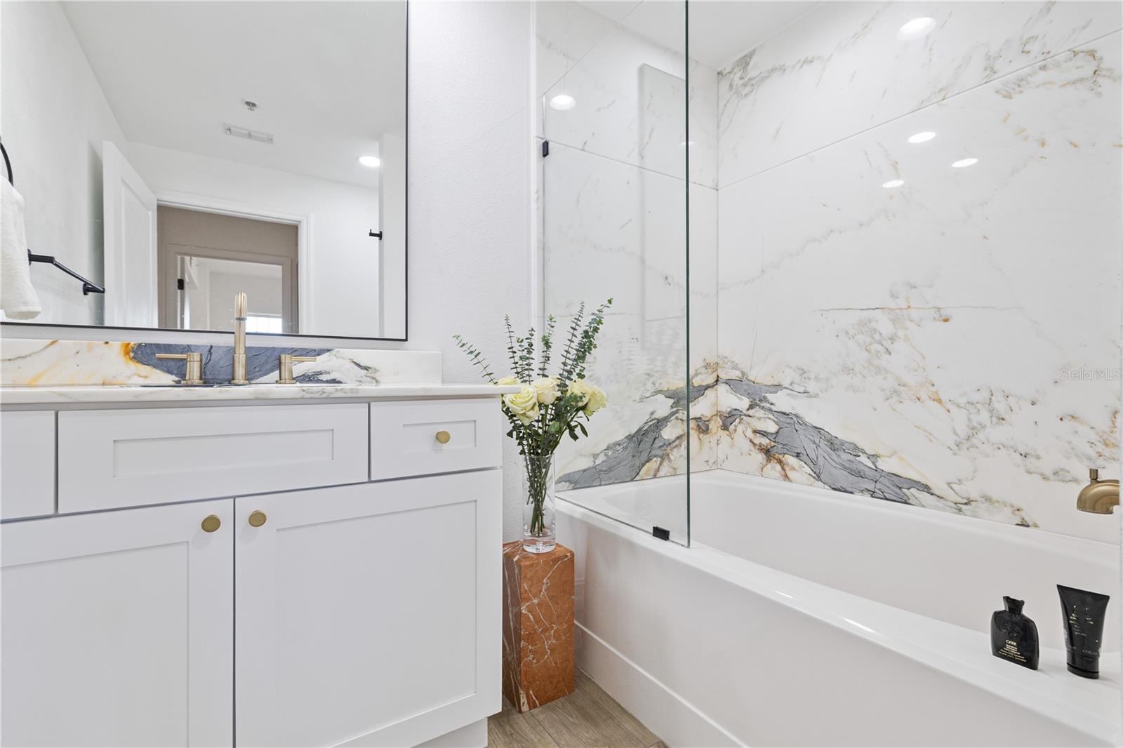 Beautifully renovated bathroom features large format marble slabs in the frameless glass shower