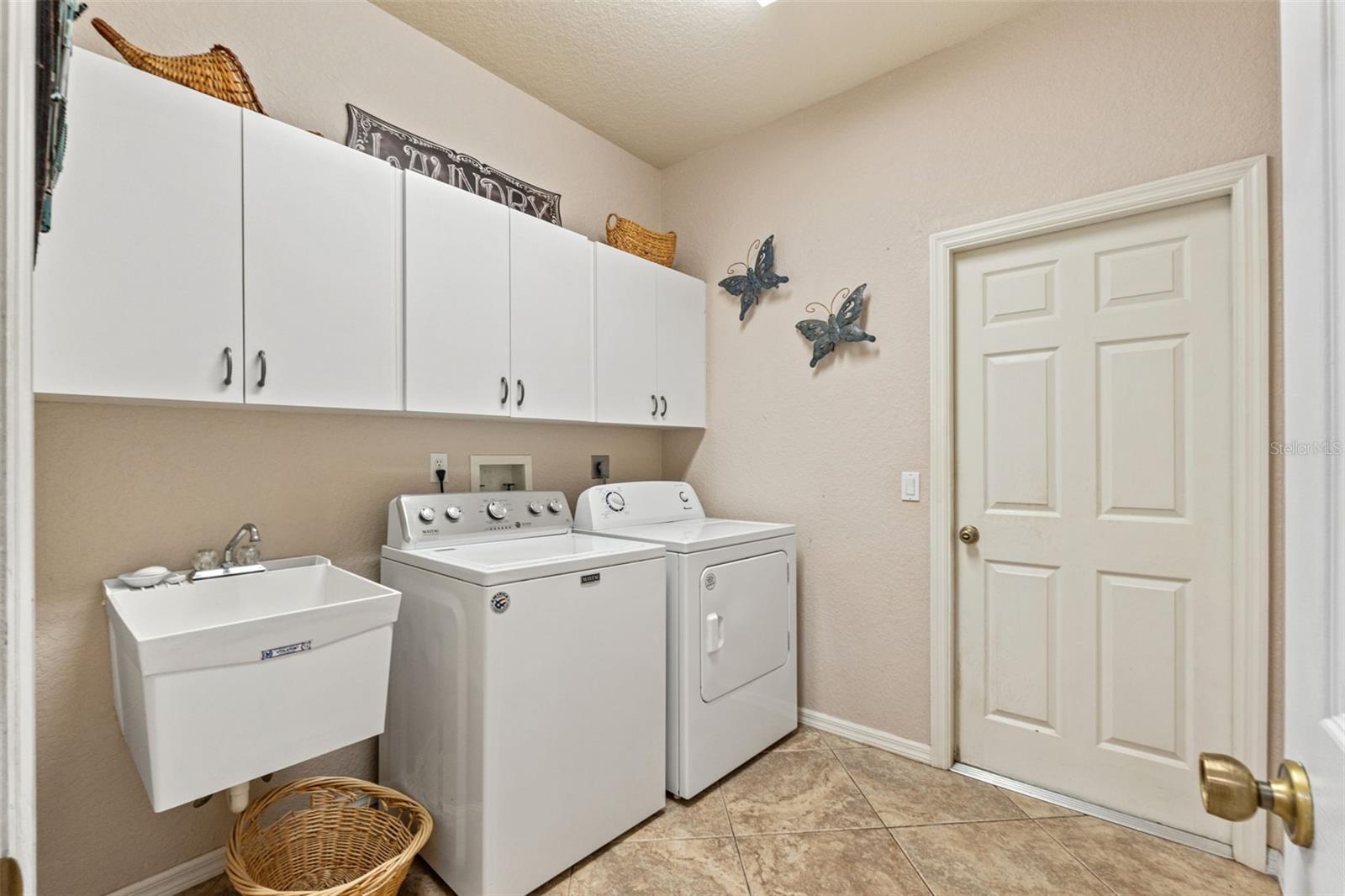 INSIDE LAUNDRY ROOM WITH CABINETS AND UTILITY TUB