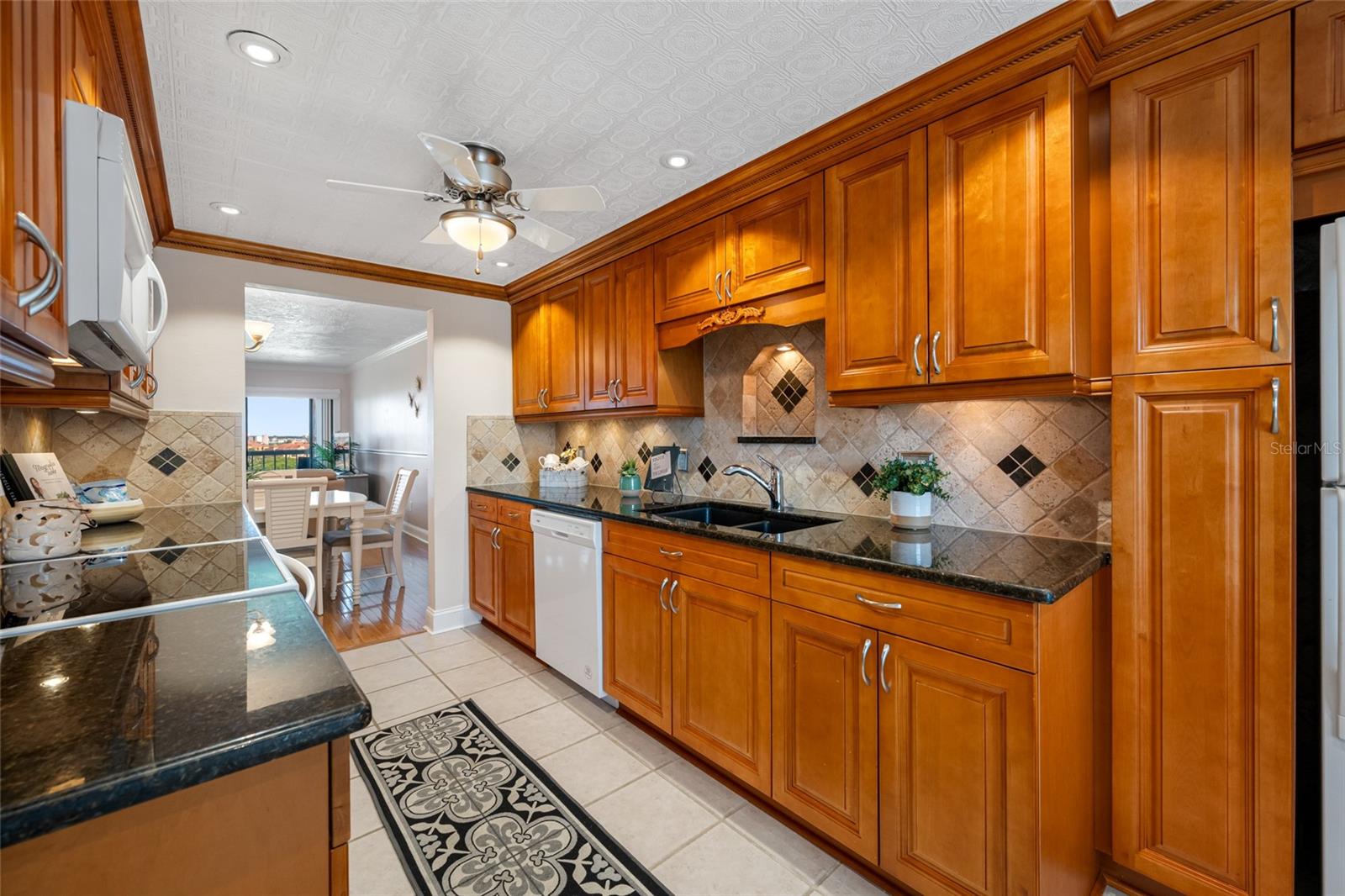 Kitchen with solid wood cabinetry, custom tile backsplash, granite countertops. Dishwasher