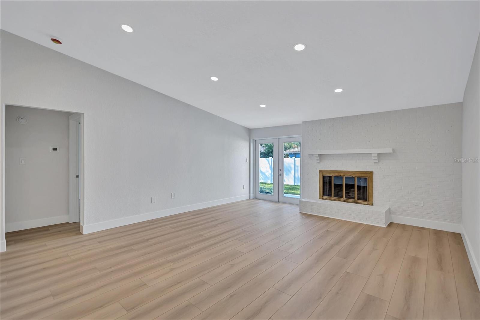 Living room with French doors to backyard, wood-burning fireplace and vaulted-ceilings.
