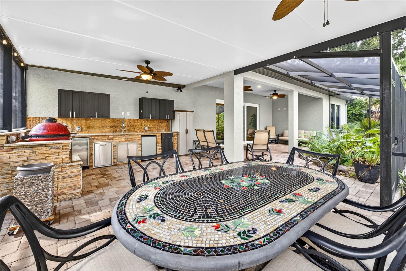 View of Covered Area that includes the Outdoor Kitchen and the Table Area with Ceiling Fans