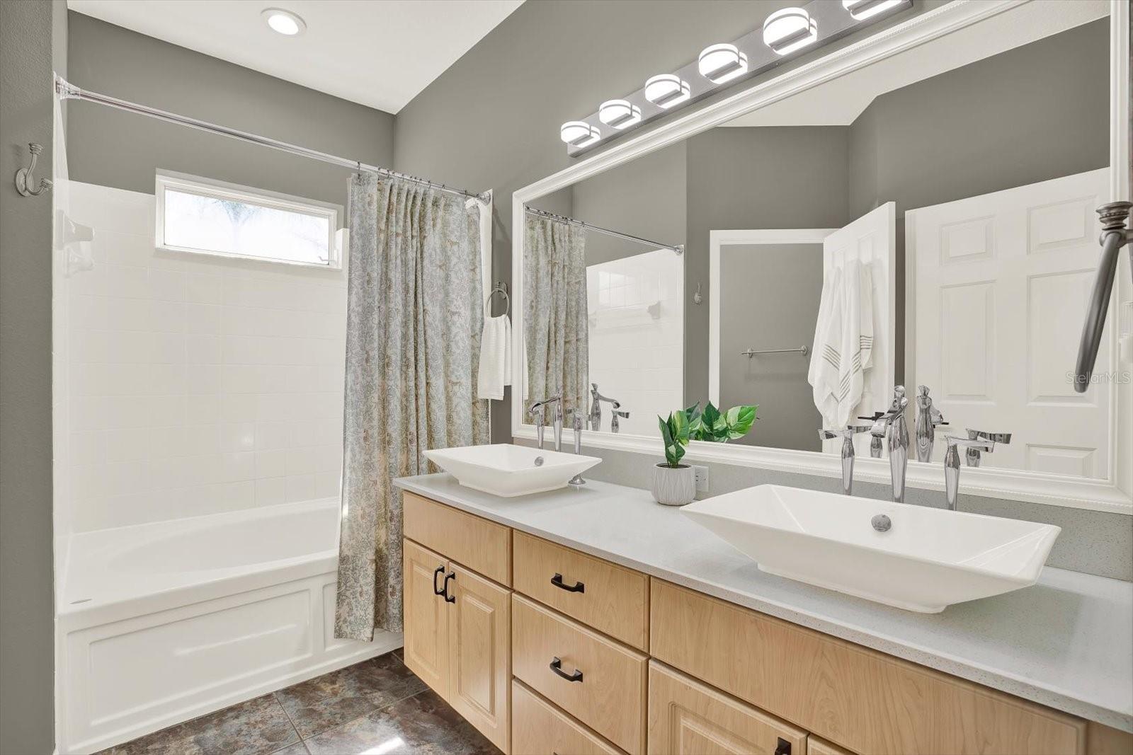 Relax and unwind in the spacious primary suite featuring an ensuite bath with dual vessel sinks, quartz counters, and a luxurious soaking tub—your private retreat after a long day.
