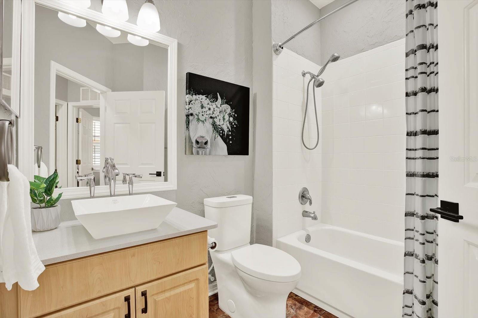 Bright and stylish guest bathroom with quartz vanity, vessel sink, and a convenient tub/shower combo—perfect for family or visitors.