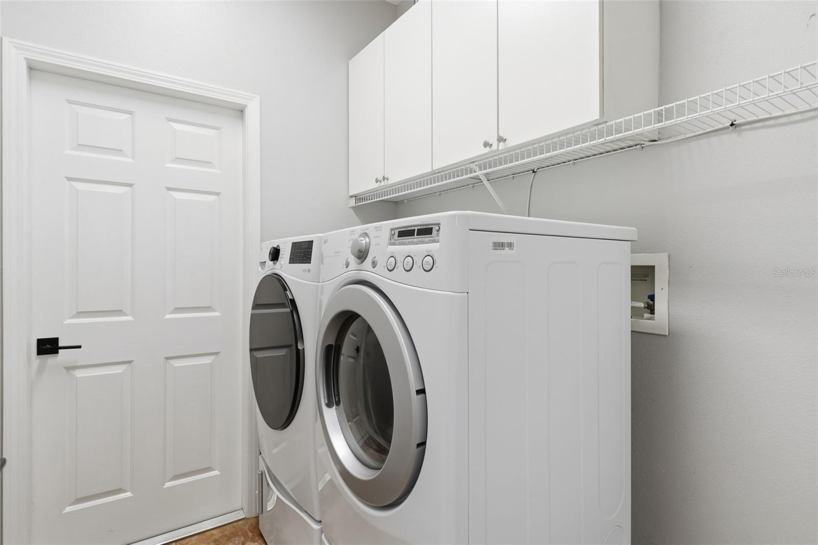 Convenient laundry room with front-load washer and dryer, upper cabinetry, and plenty of storage to keep things organized and tidy.