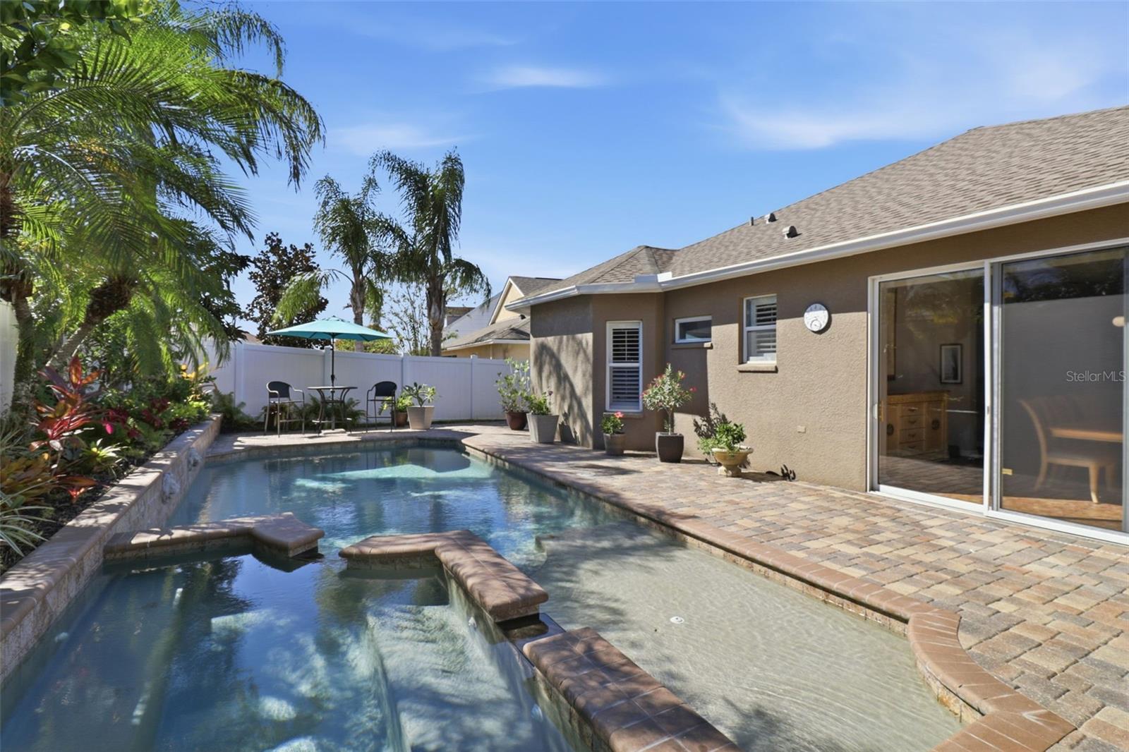 Expansive paver patio surrounds the heated saltwater pool and spa, creating a seamless indoor-outdoor flow perfect for entertaining.