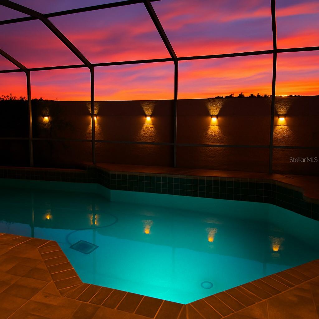 Sunset view of pool and solar lights on wall