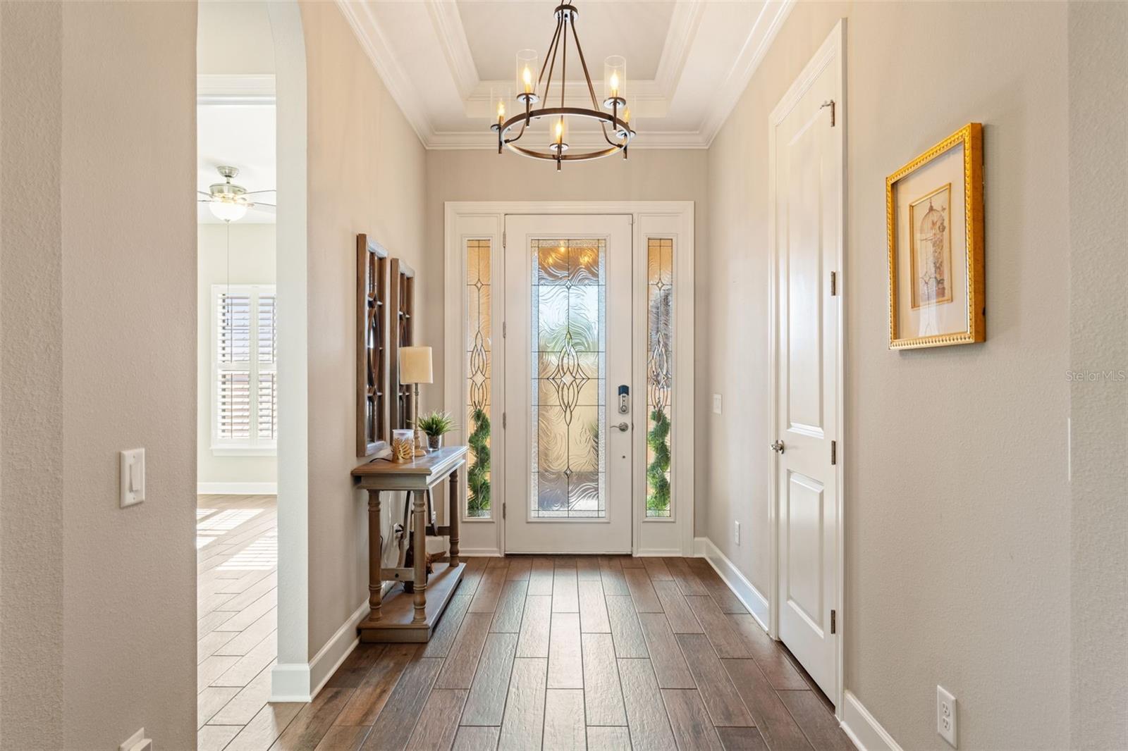 Underfoot is rich hardwoodesque tile flooring, detailed crown molding, and arched entries that lead the eye toward the open-concept living spaces beyond.