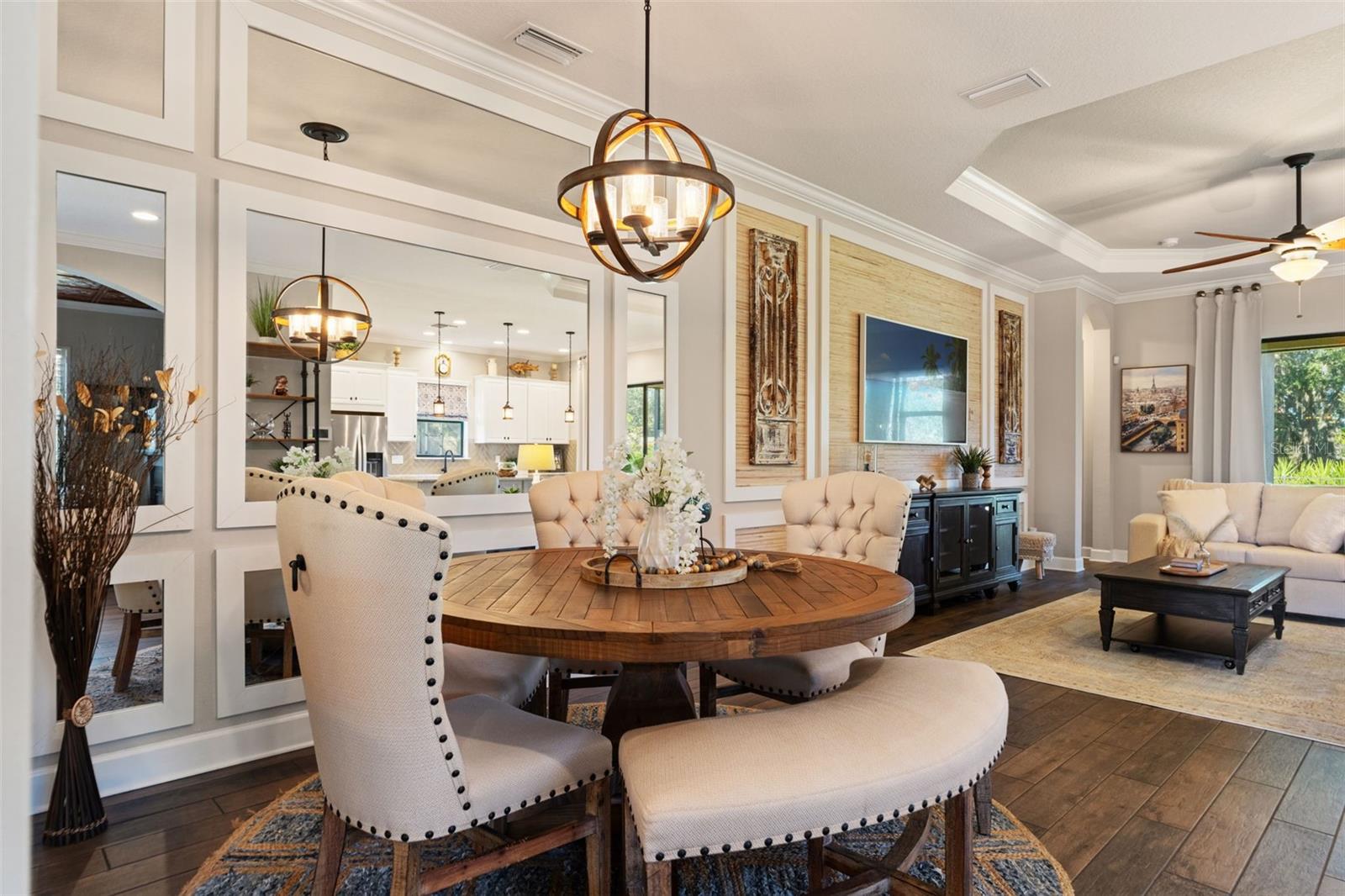 Dining area framed by mirrored millwork, statement lighting, and seamless flow to the kitchen.