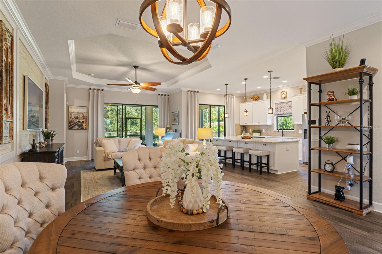Open living and dining area with porcelain tile floors, tray ceiling, and expansive conservation views.