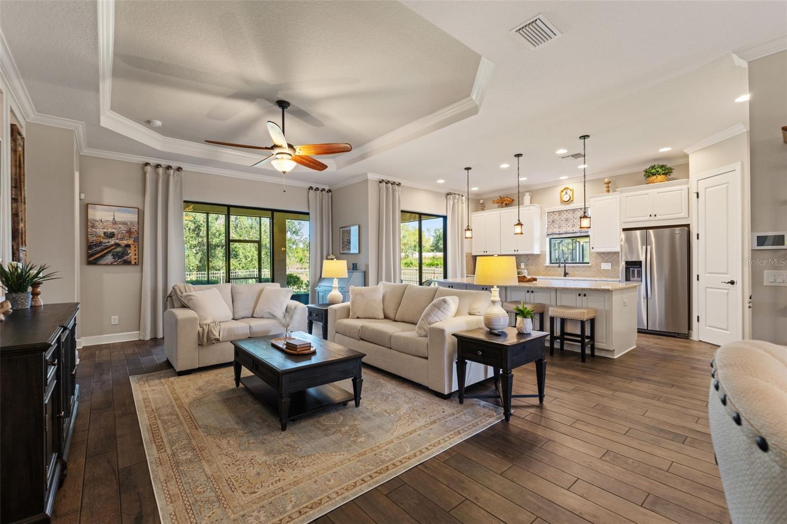 Living room with coffered ceiling, recessed lighting, and sliders opening to the screened lanai.