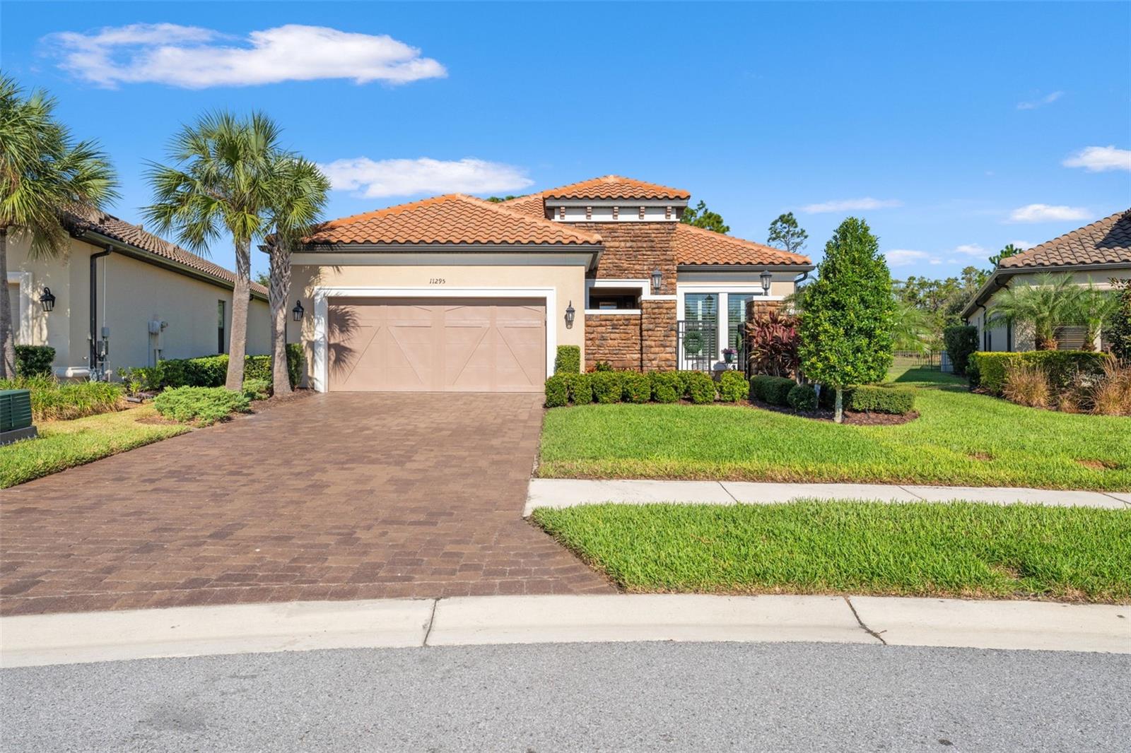 Stunning front elevation with lush landscaping, manicured hedges, and a gated courtyard entry creating both elegance and privacy.