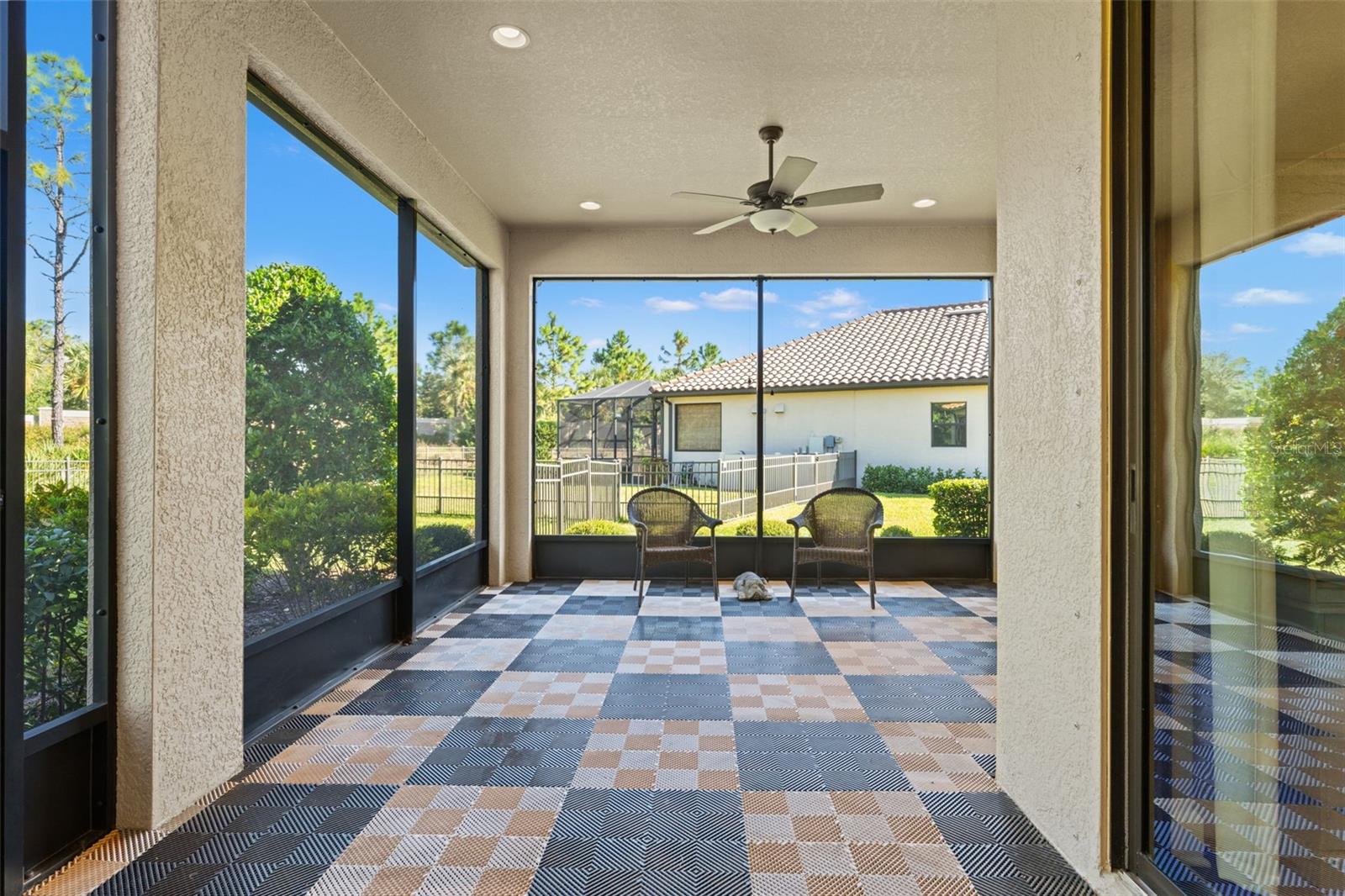 Expansive screened lanai with upgraded tile-look flooring, recessed lighting, and tranquil conservation views—perfect for morning coffee or evening relaxation.
