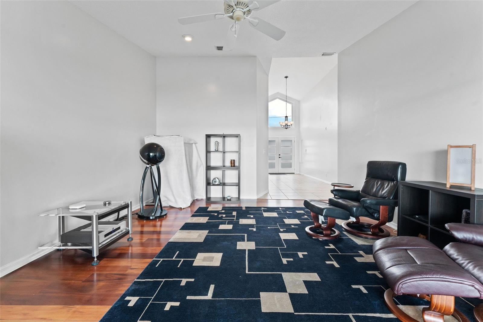 Formal living room with soaring vaulted ceilings and hardwood floors, creating a grand and inviting space.
