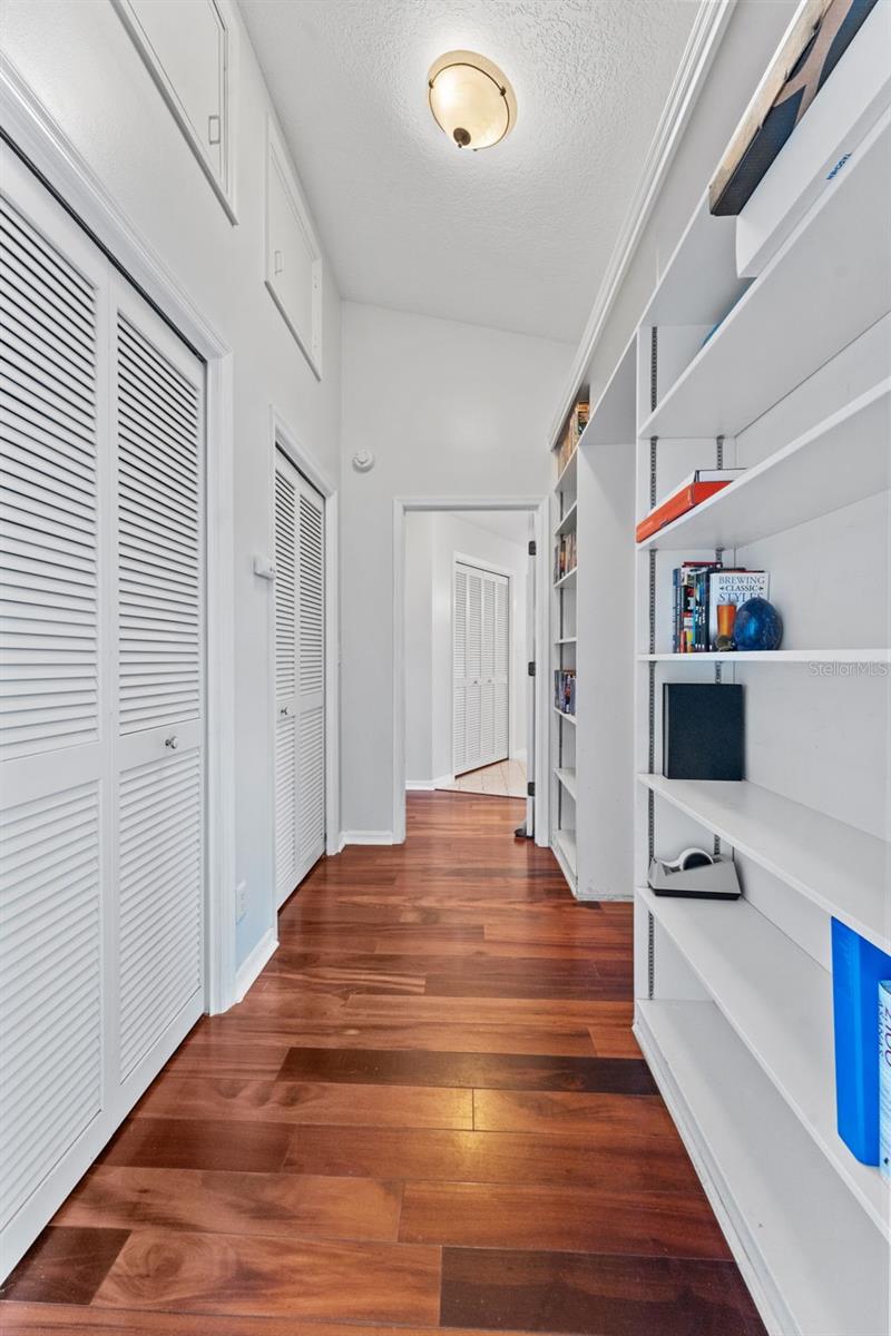 Hallway featuring built-in shelving and extra closet space, leading to Bedroom 2 and the luxurious primary suite.