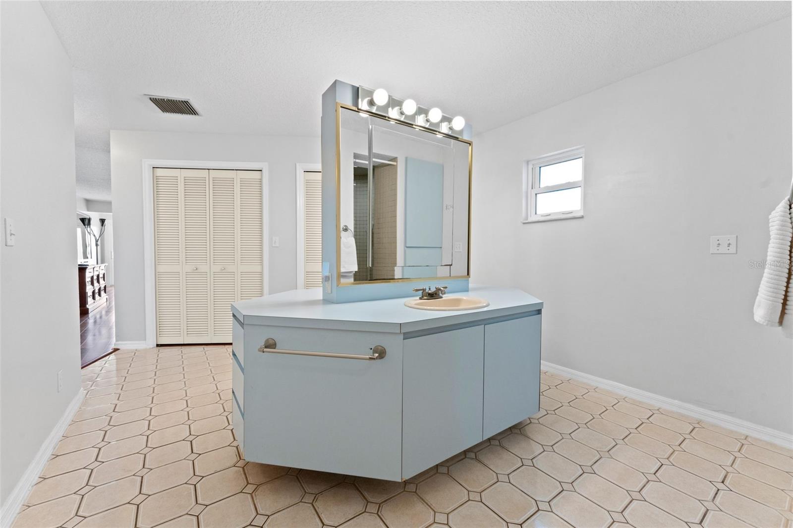 Primary bathroom with convenient closet doors that lead directly to a large walk-in closet for effortless organization.