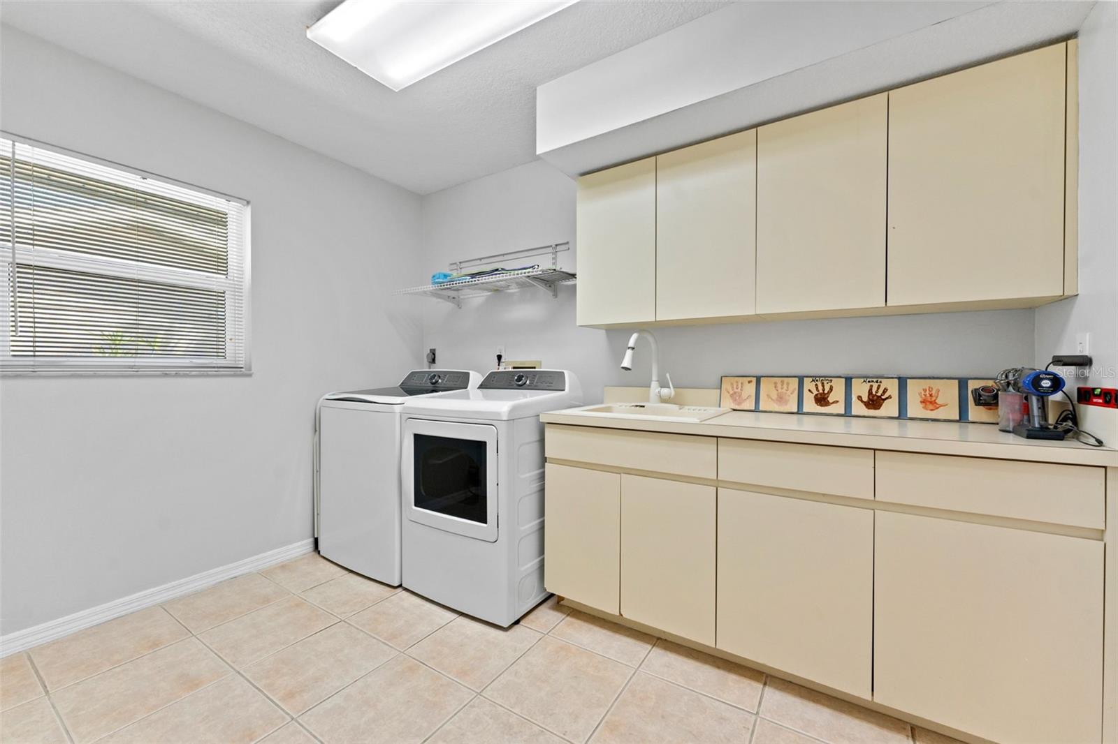 Spacious laundry room with a new washer and dryer, offering plenty of room for organization and daily tasks.