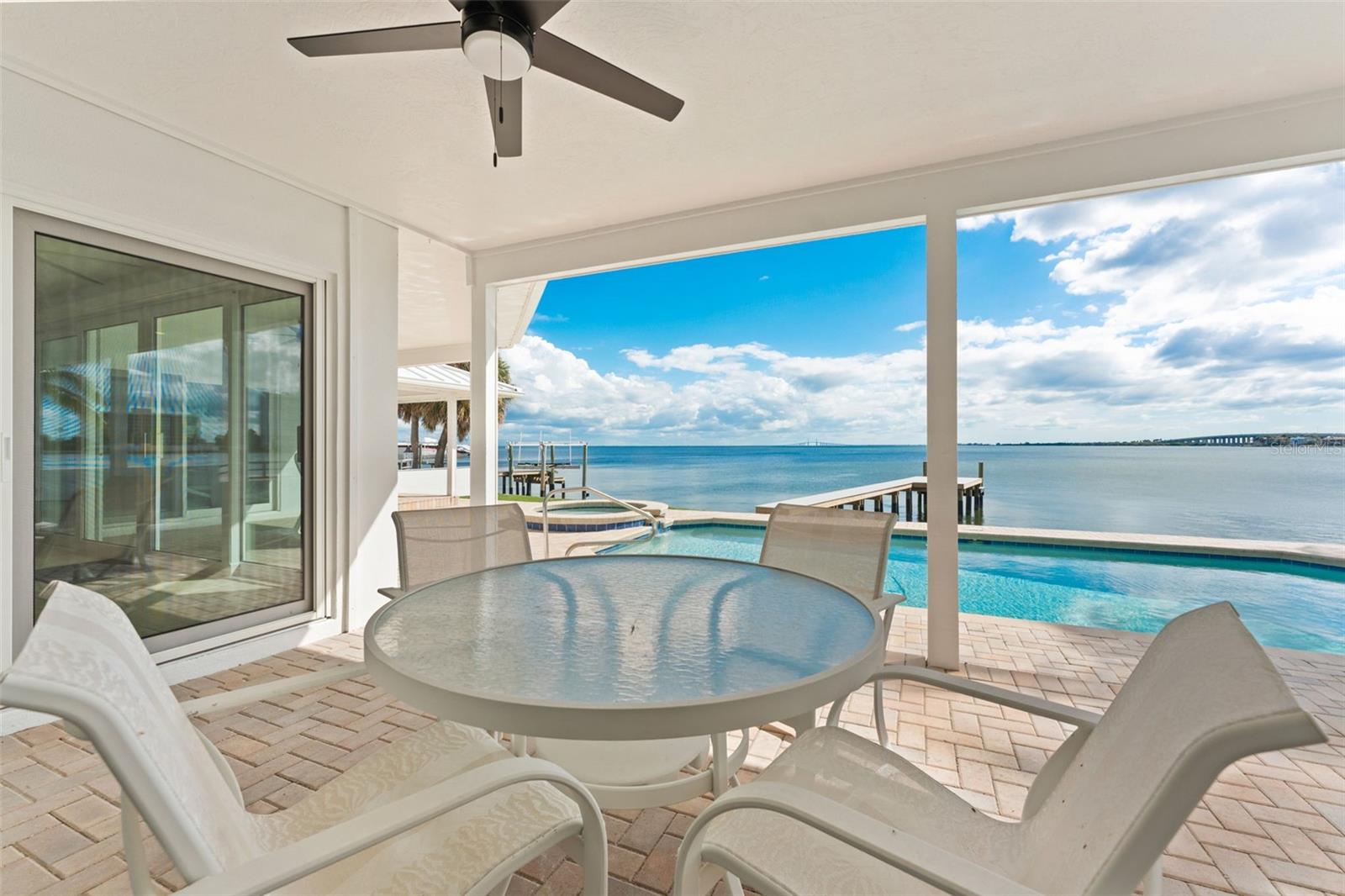 Covered back patio with stunning views of the pool and Tampa Bay, perfect for enjoying the outdoors in comfort.