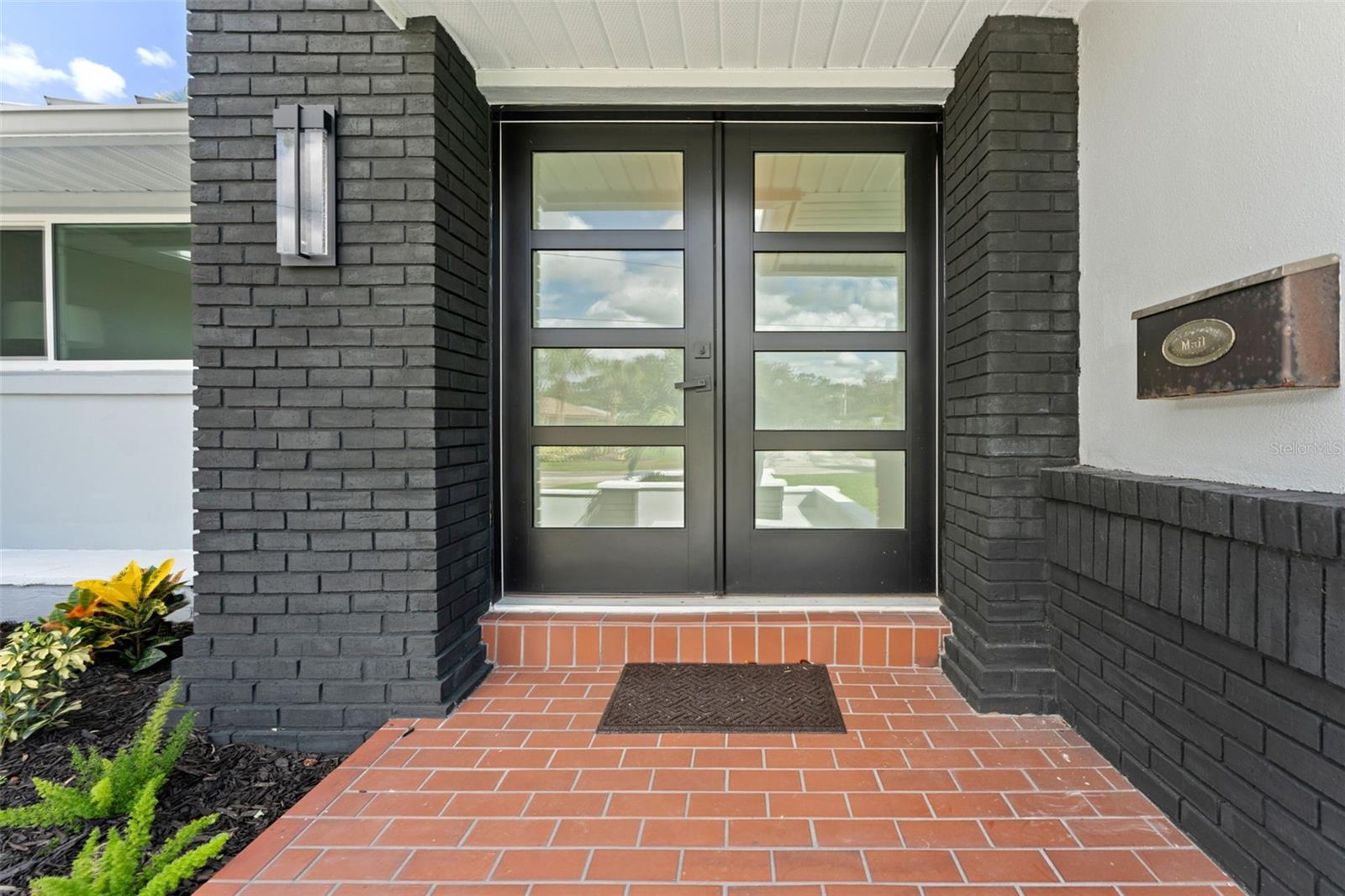 Modern double glass doors create a grand and inviting entry with a sleek, contemporary touch.
