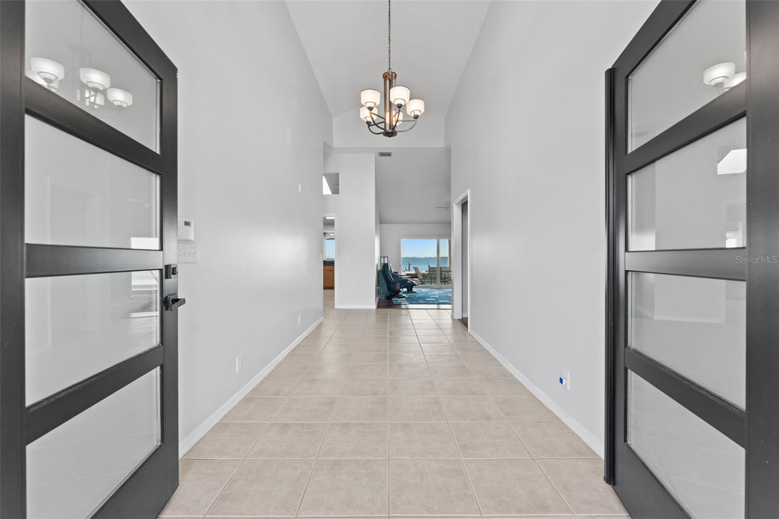 Welcoming front entry with double doors opening to an inviting foyer featuring vaulted ceilings and abundant natural light.