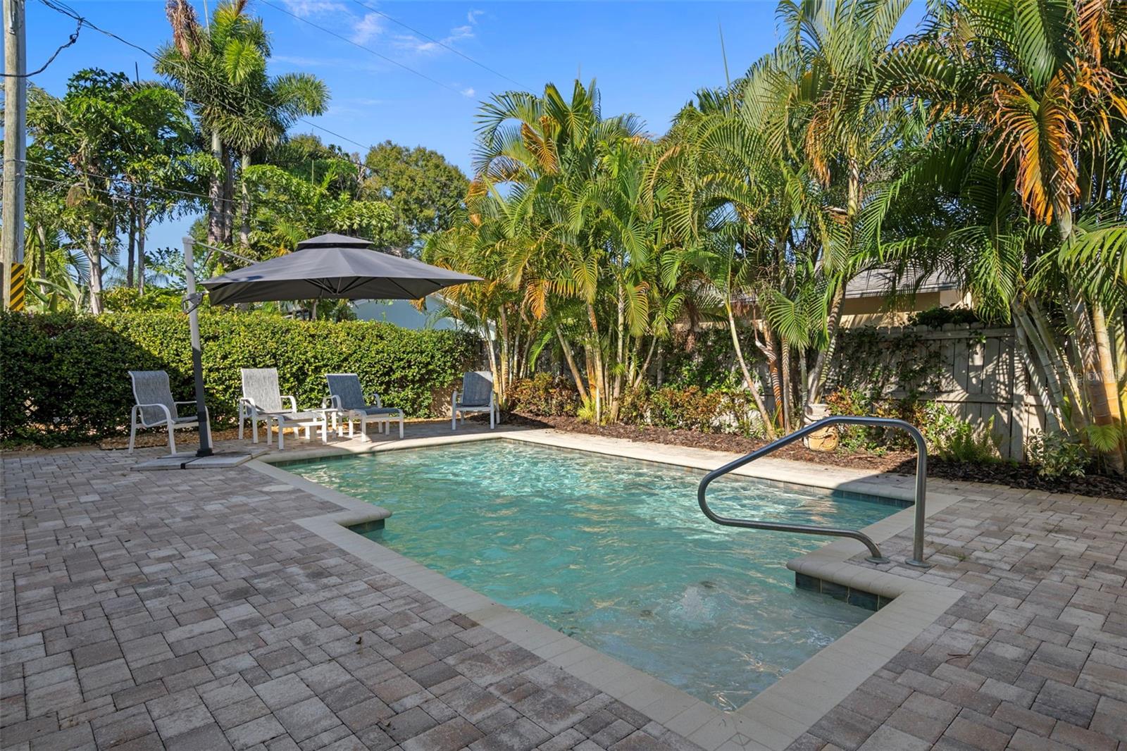 Private backyard oasis with a saltwater pool, lush tropical landscaping, and plenty of space for entertaining.