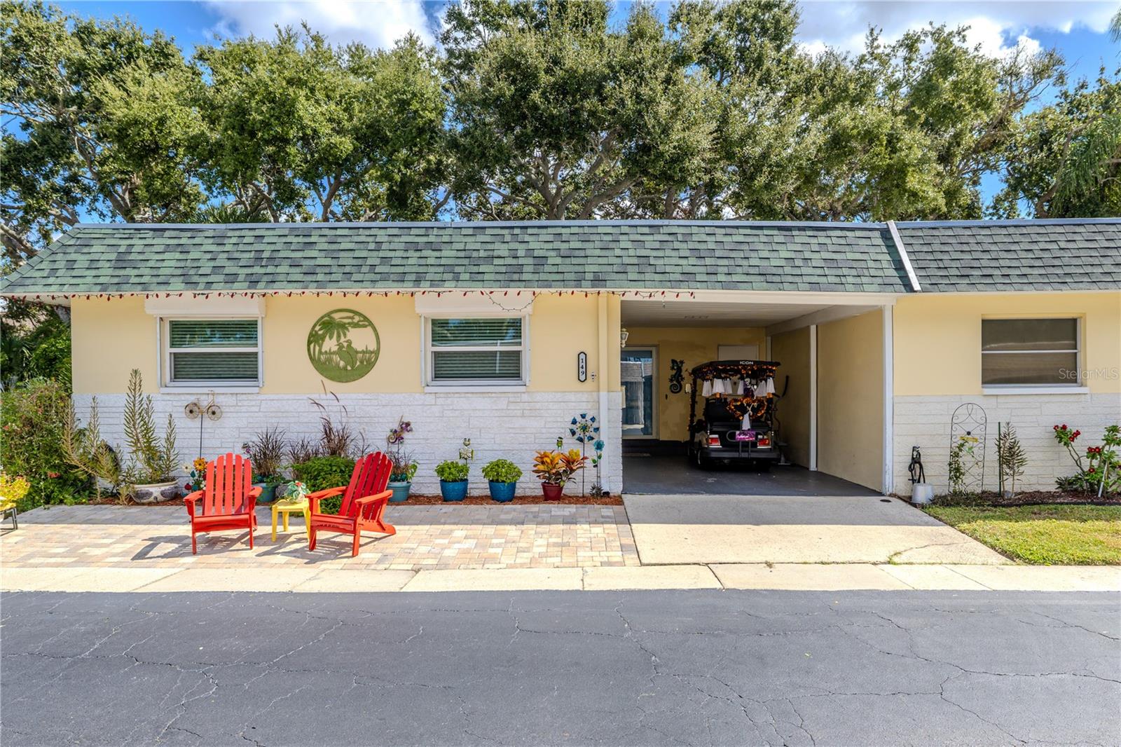 Inviting front elevation framed by lush greenery and colorful landscaping. End-unit location offers privacy, easy parking, and welcoming curb appeal.